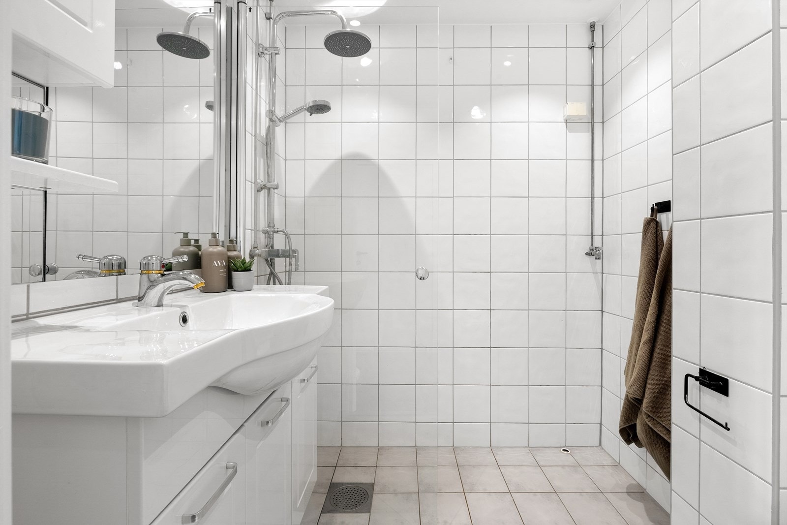 Pent og lyst flislagt bad med opplegg for vaskemaskin. Galleribilde