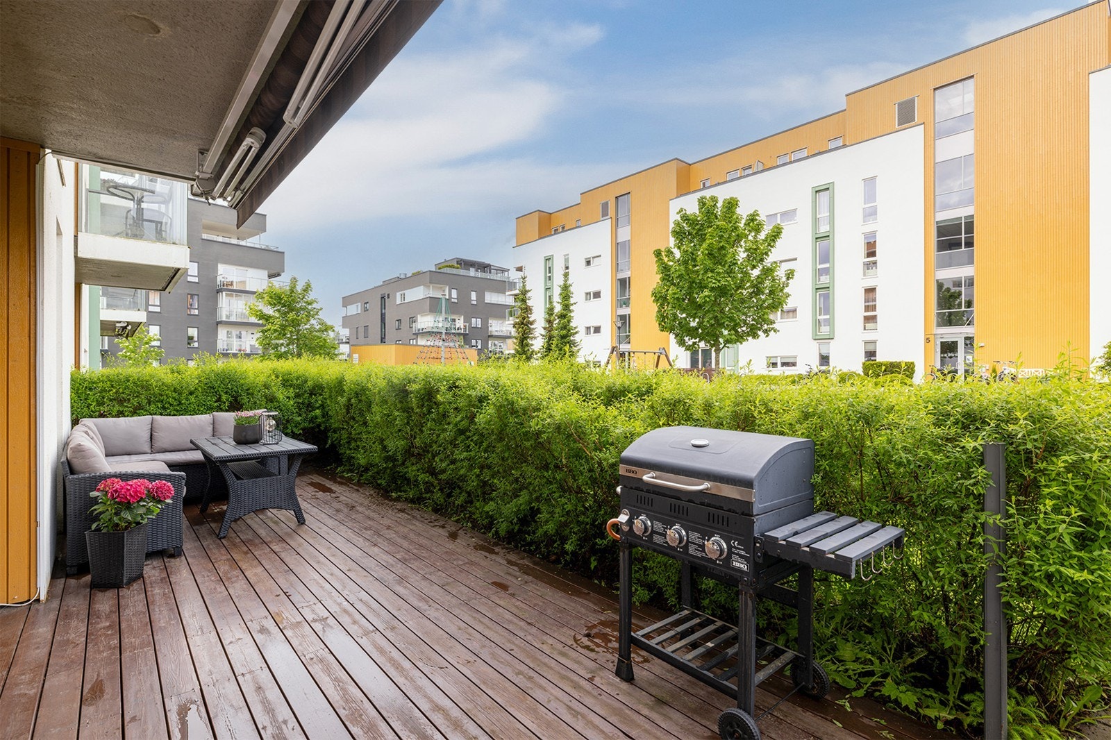 Terrassen er pent omkranset av en hekk, delvis overbygget og utstyrt med markise. Galleribilde