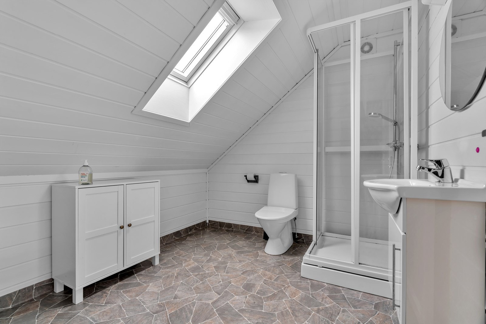 Badet på loftet har vinylbelegg på gulv og er utstyrt med dusjkabinett, toalett og servant. Galleribilde