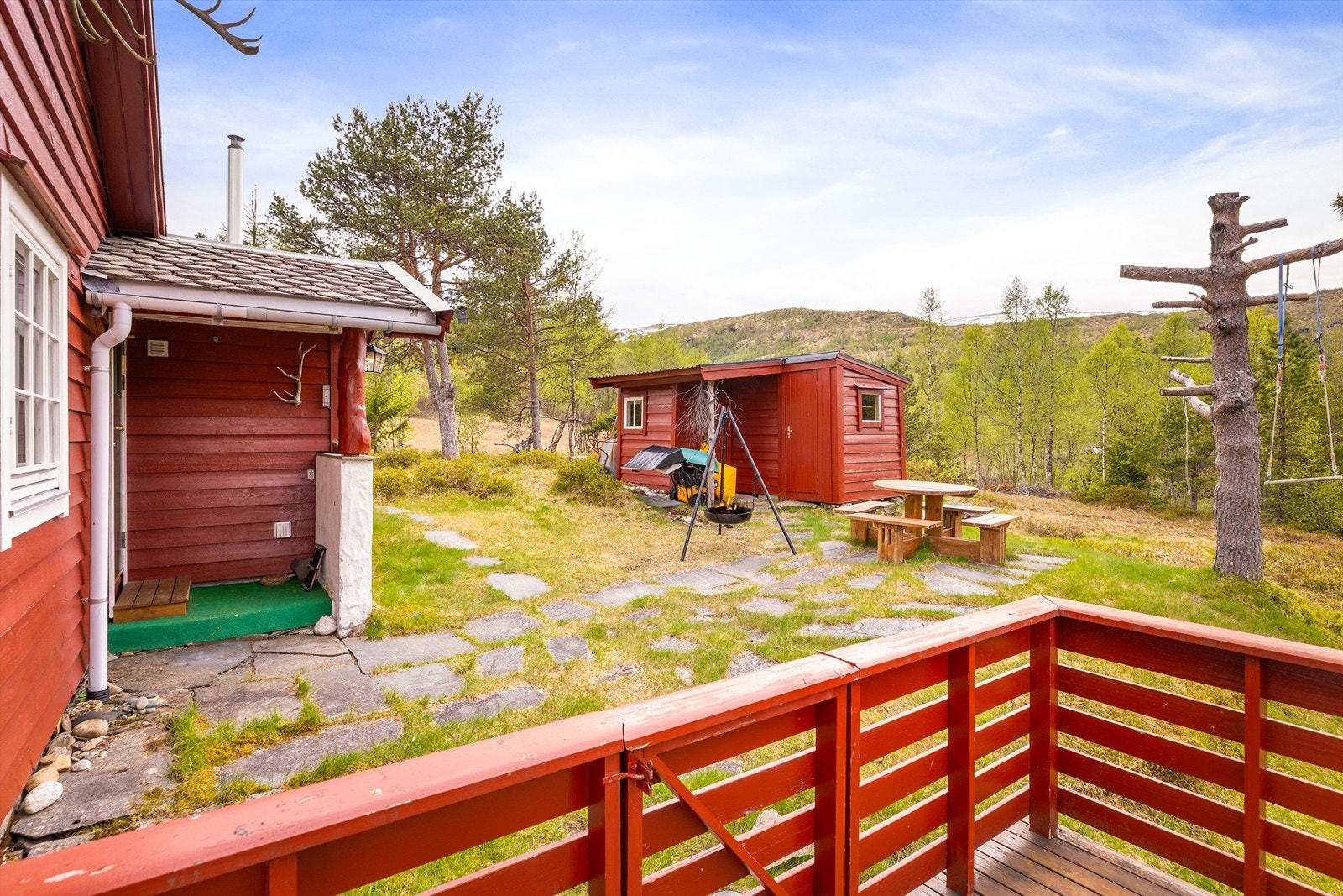Stor naturtomt med hellelagt gangsti mellom hytten og uteboden. Galleribilde