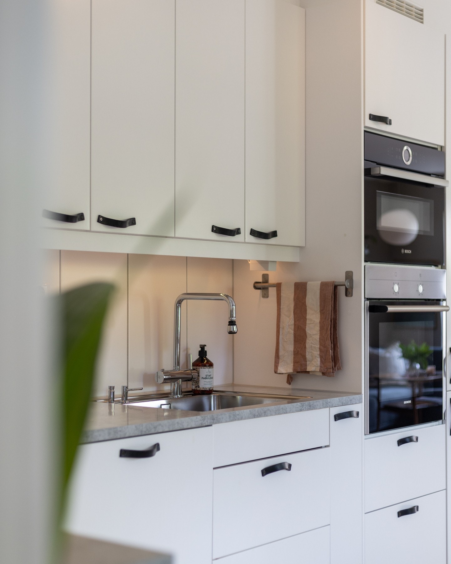 Lys, glatt innredning med egenproduserte håndtak av skinn laget av salmaker, laminat benkeplate og oppvaskkum. Galleribilde