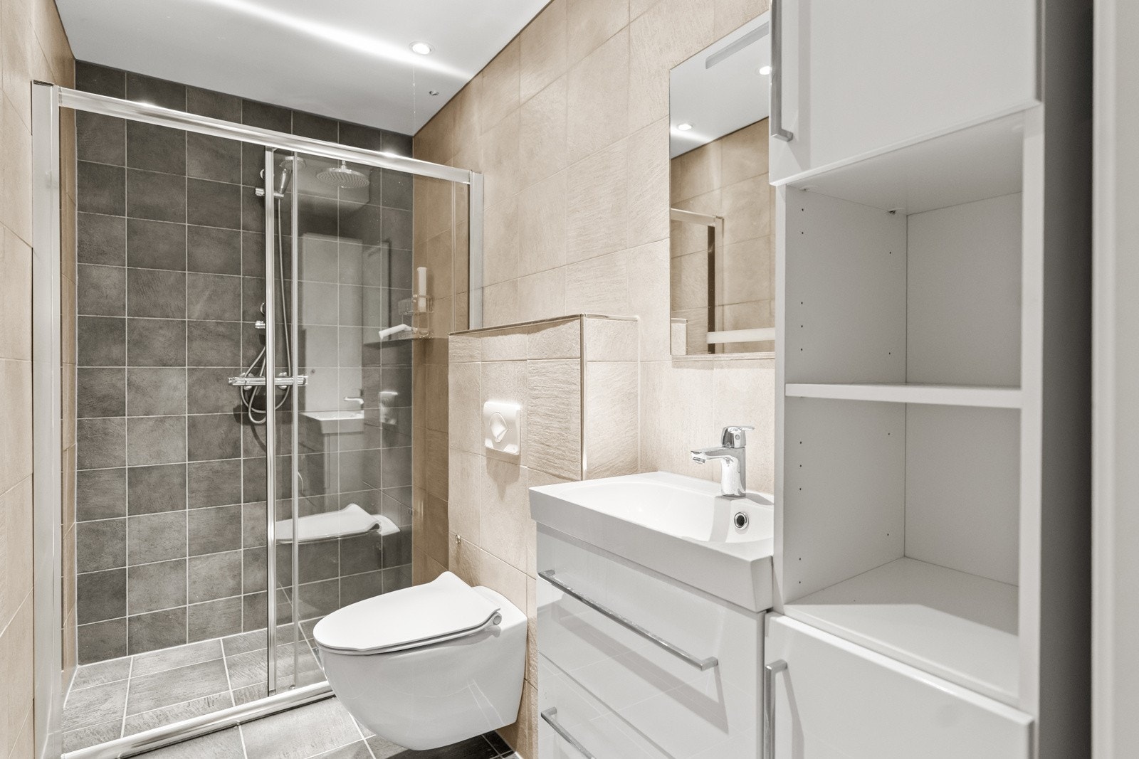 Flislagt bad i med vannbåren gulvvarme. Badet har innredning med skuffer og heldekkende servant. Det er vegghengt toalett og en romslig dusjløsning med skyvedører. Veggmontert høyskap. Det er mekanisk ventilasjon med avtrekk. Galleribilde