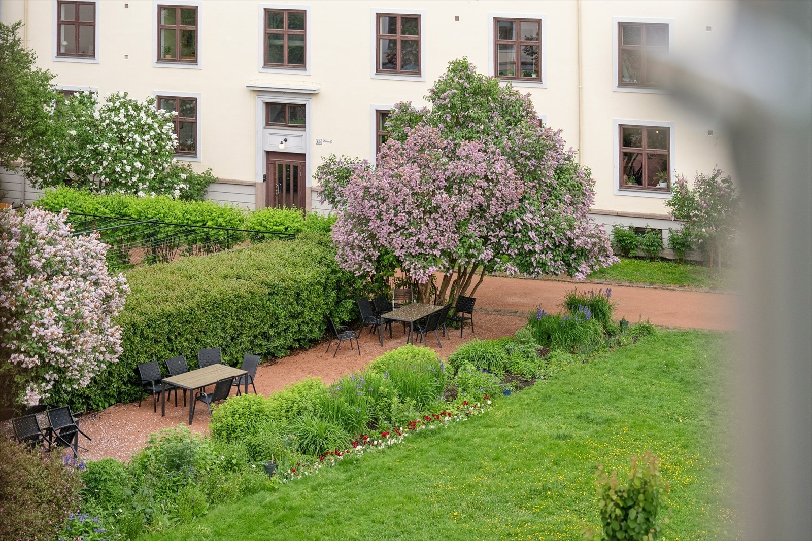 Utsikt fra stuen. Den pent opparbeidede bakgården har flere sittegrupper og felles grill tilgjengelig for beboerne. Galleribilde