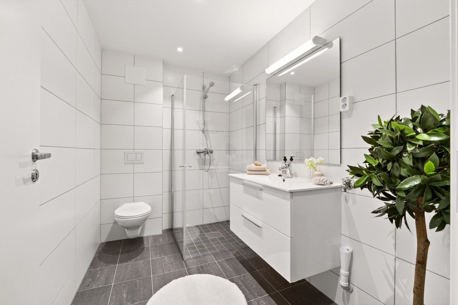De store flislagte overflatene på gulv og vegger skaper et eksklusivt uttrykk og gir badet et tidløst preg som vil stå seg godt i mange år fremover. Galleribilde