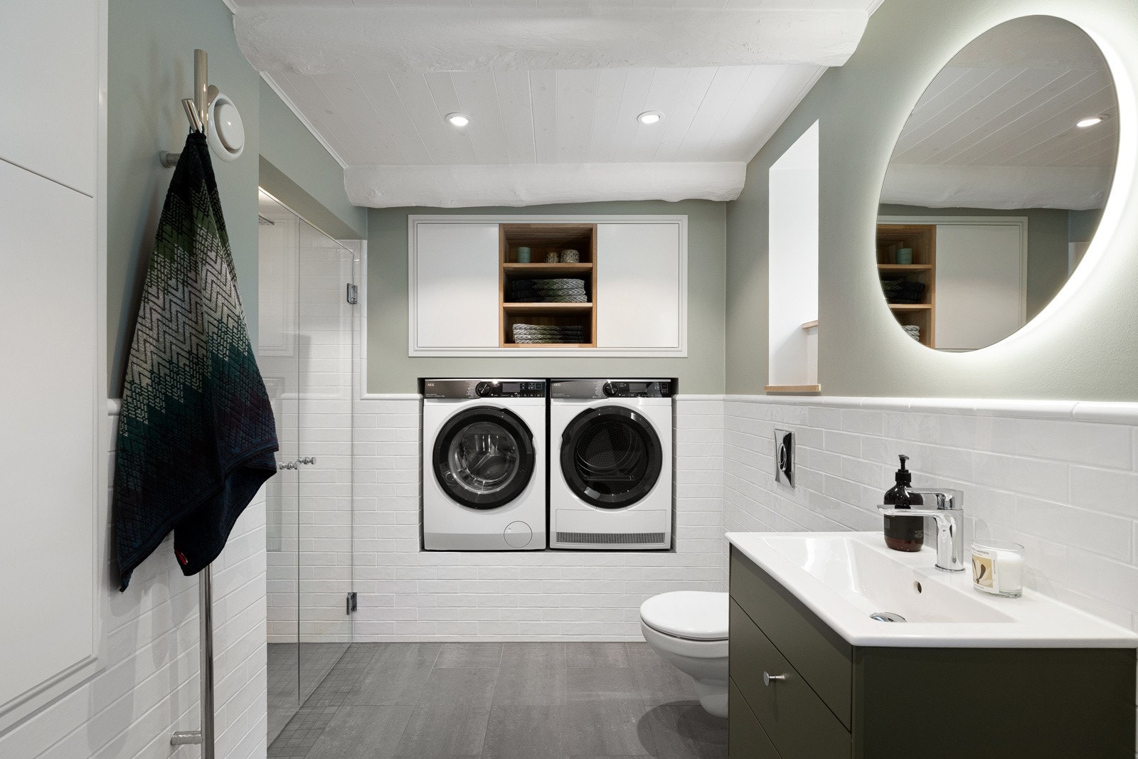 Badet i underetasjen er praktisk og pent utformet med romslig dusjsone, glassdører, vegghengt toalett, servantinnredning, speil med belysning og opplegg for vaskemaskin og tørketrommel. Galleribilde