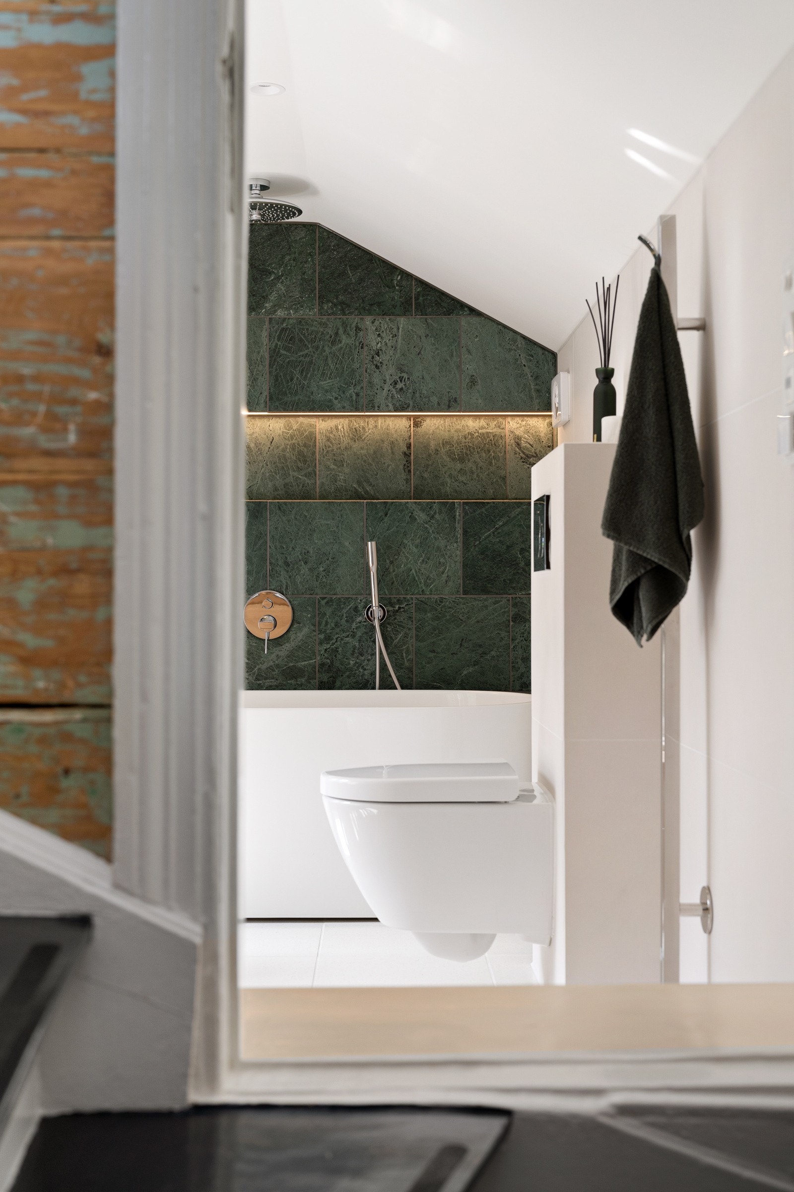 Badet har en svært gjennomført materialpalett med dype grønne marmorfliser fra Italia som strekker seg opp mot den skrå himlingen og skaper et markant og elegant uttrykk. Galleribilde
