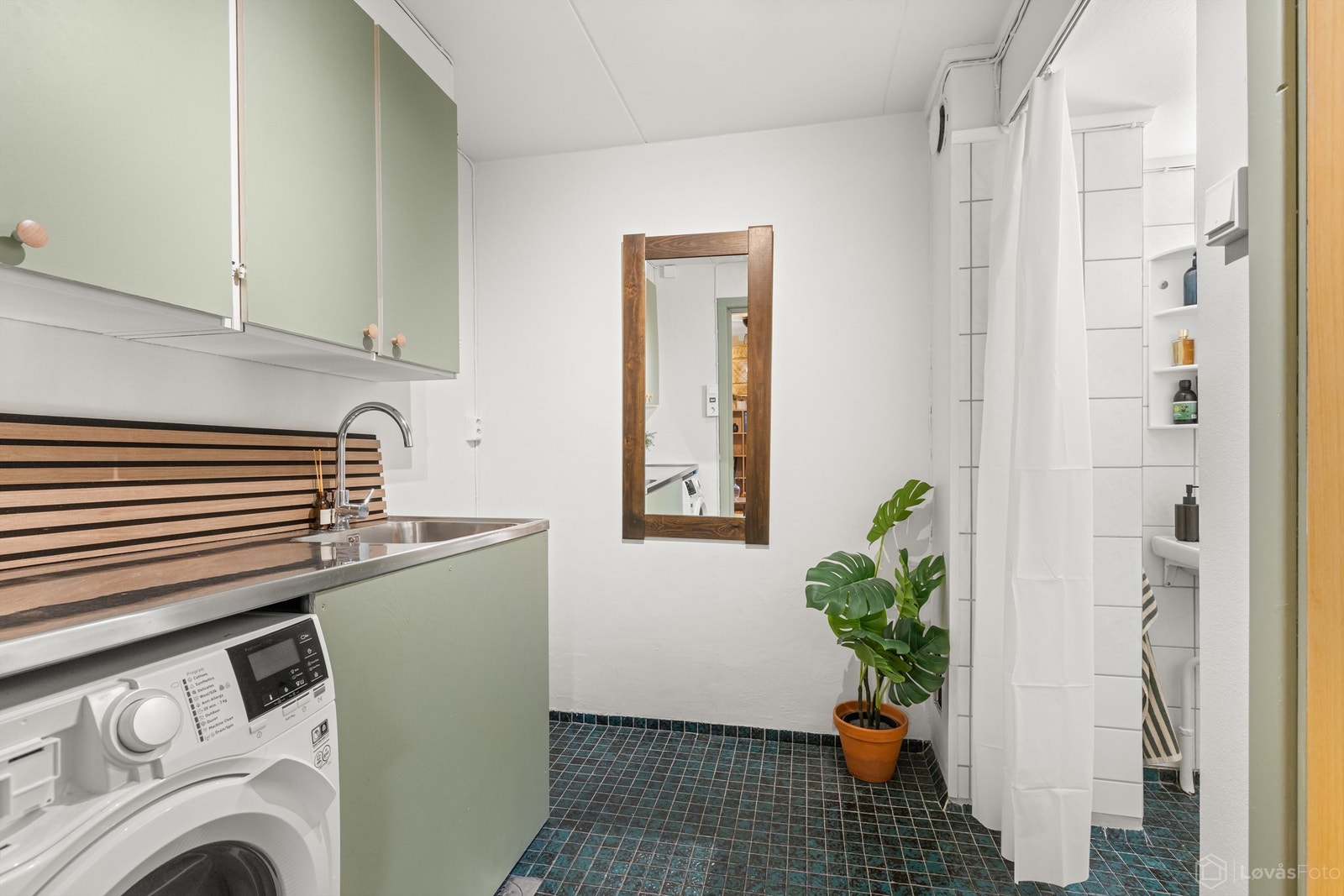 Bad i underetasjen med flislagt gulv med gulvvarme. Badet er utstyrt med vegghengt servant, speilskap med overlys, gulvstående innredning med benkeplate, nedfelt utslagsvask, dusjnisje og toalett, og opplegg for vaskemaskin. Galleribilde