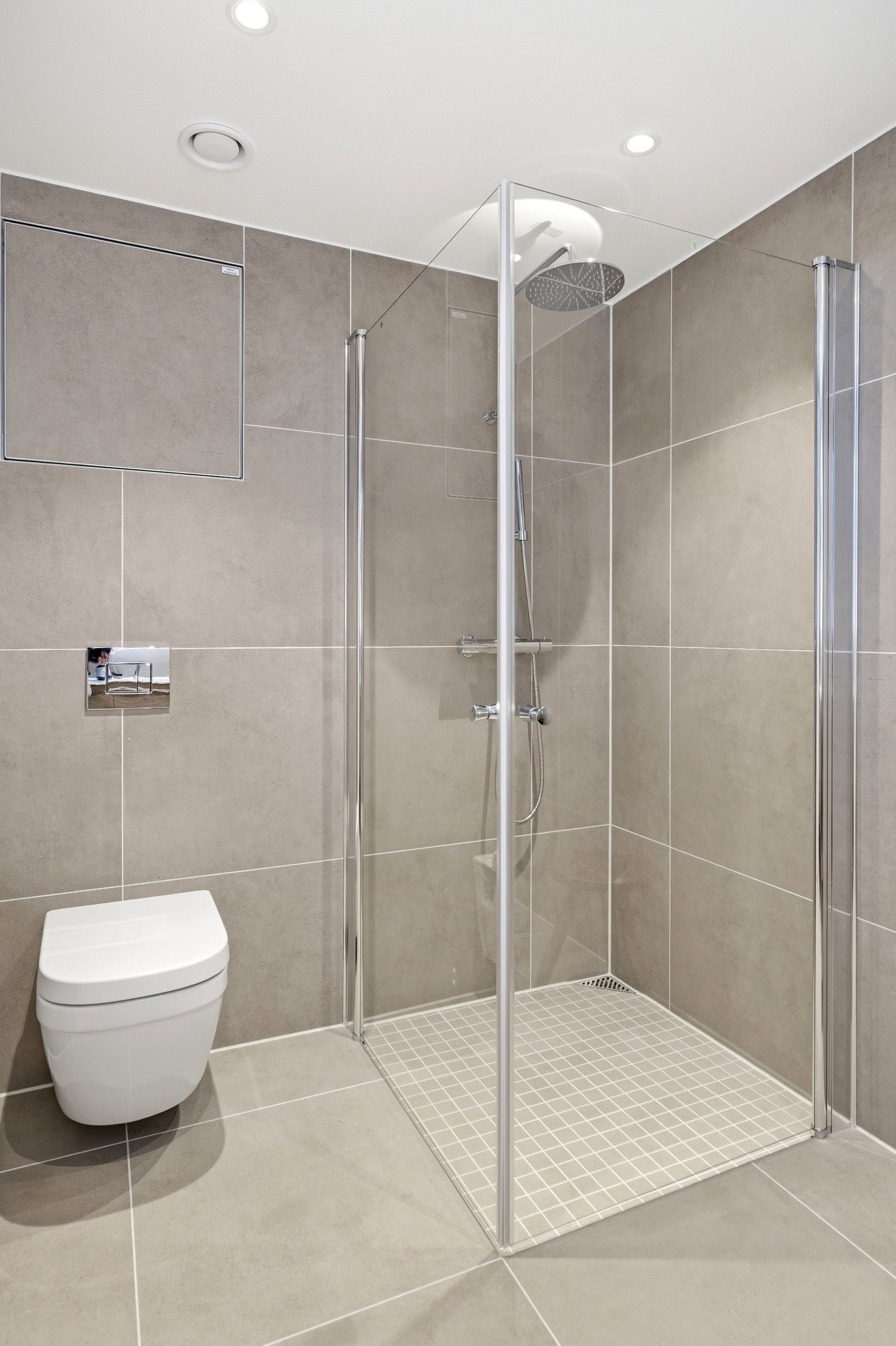 Dusjhjørne med takdusj og vegger som kan slås inn. Vegghengt toalett fra Grohe med soft close Galleribilde