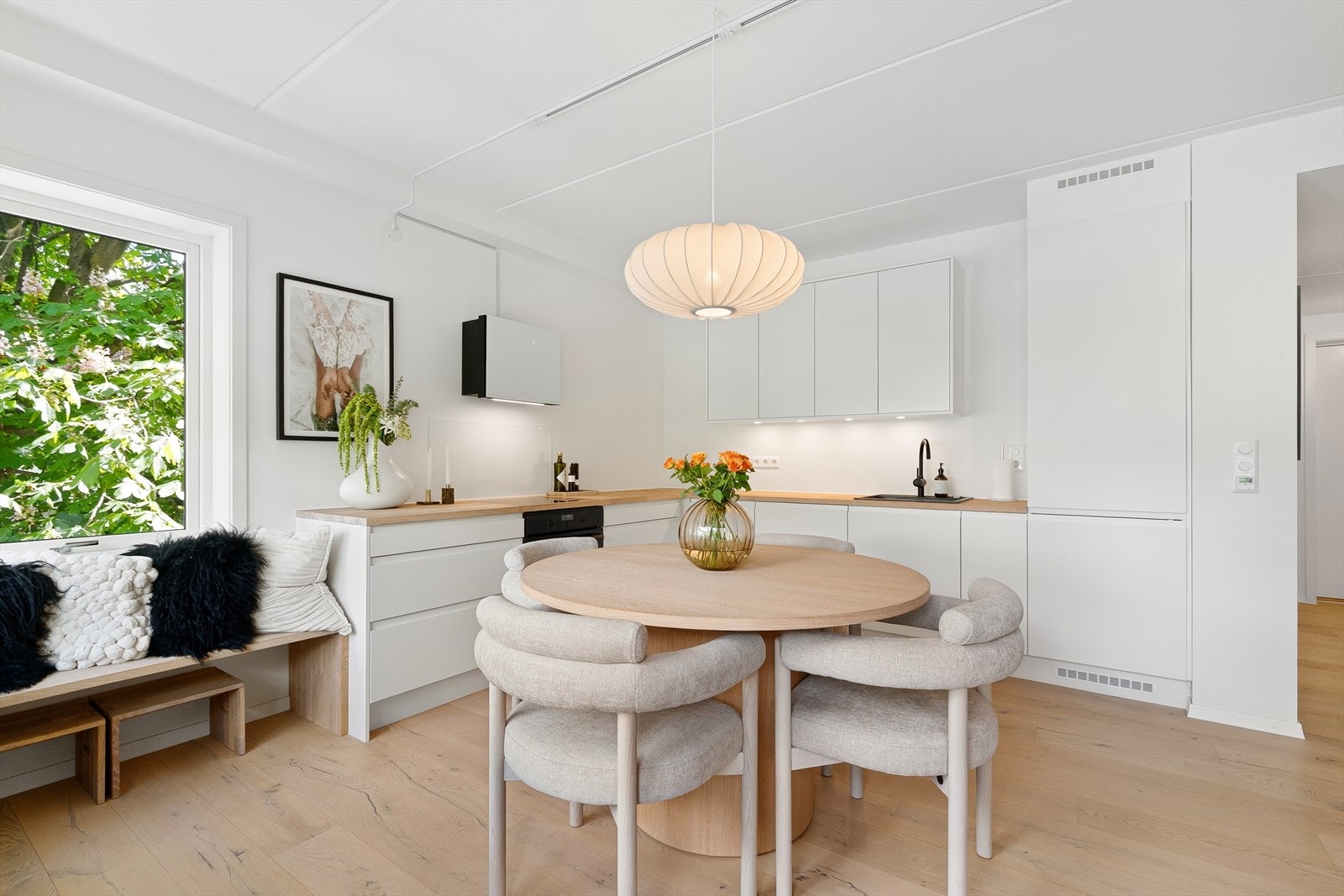 Stilsikker innredning fra 2024 med glatte, hvite fronter med integrerte gripehåndtak og benkeplate i heltre. Galleribilde