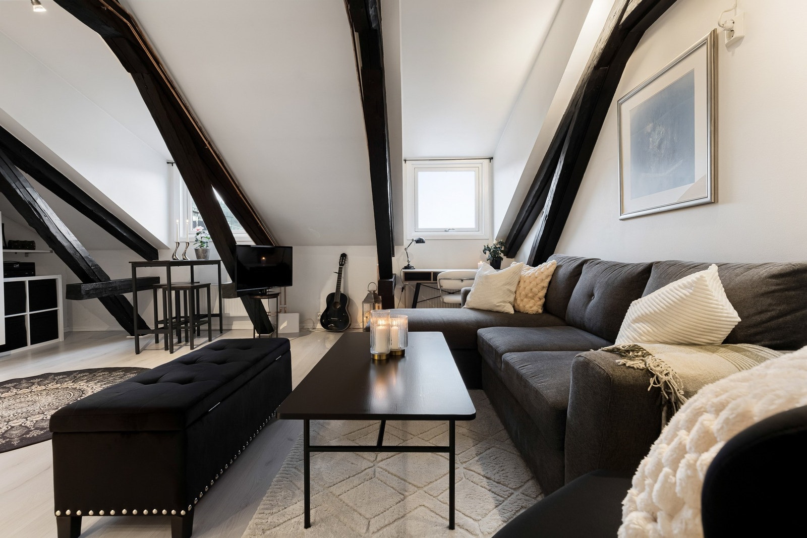 Stilfulle kontraster skapes med sortmalte, kraftige bjelker mot de hvitmalte overflatene, og allrommet har lys, tidsmessig laminat på gulvet. Galleribilde