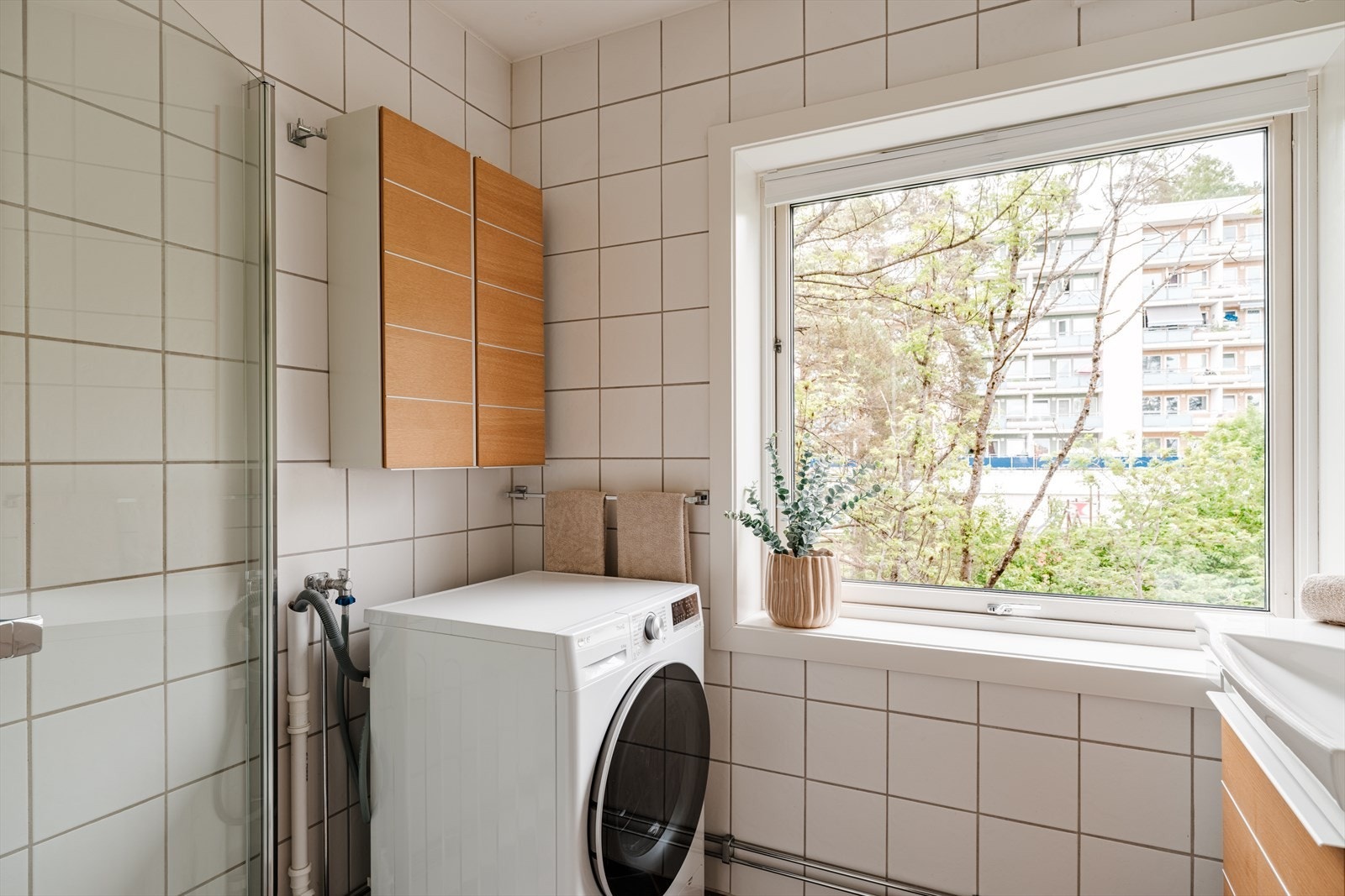 Badet er flislagt med varmekabler i gulv og opplegg for vaskemaskin. Det er servant med innredning til oppbevaring Galleribilde