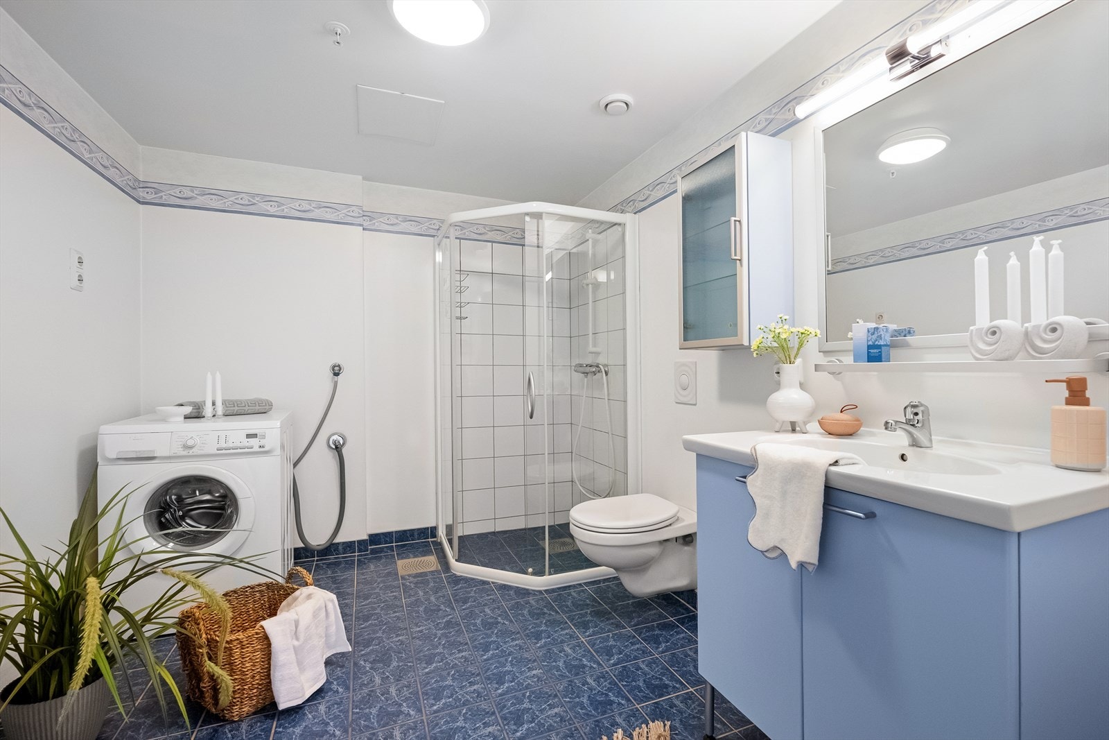 Badet har flislagt gulv med vannbåren varme, dusjhjørne med glassvegger og opplegg for vaskemaskin. Galleribilde