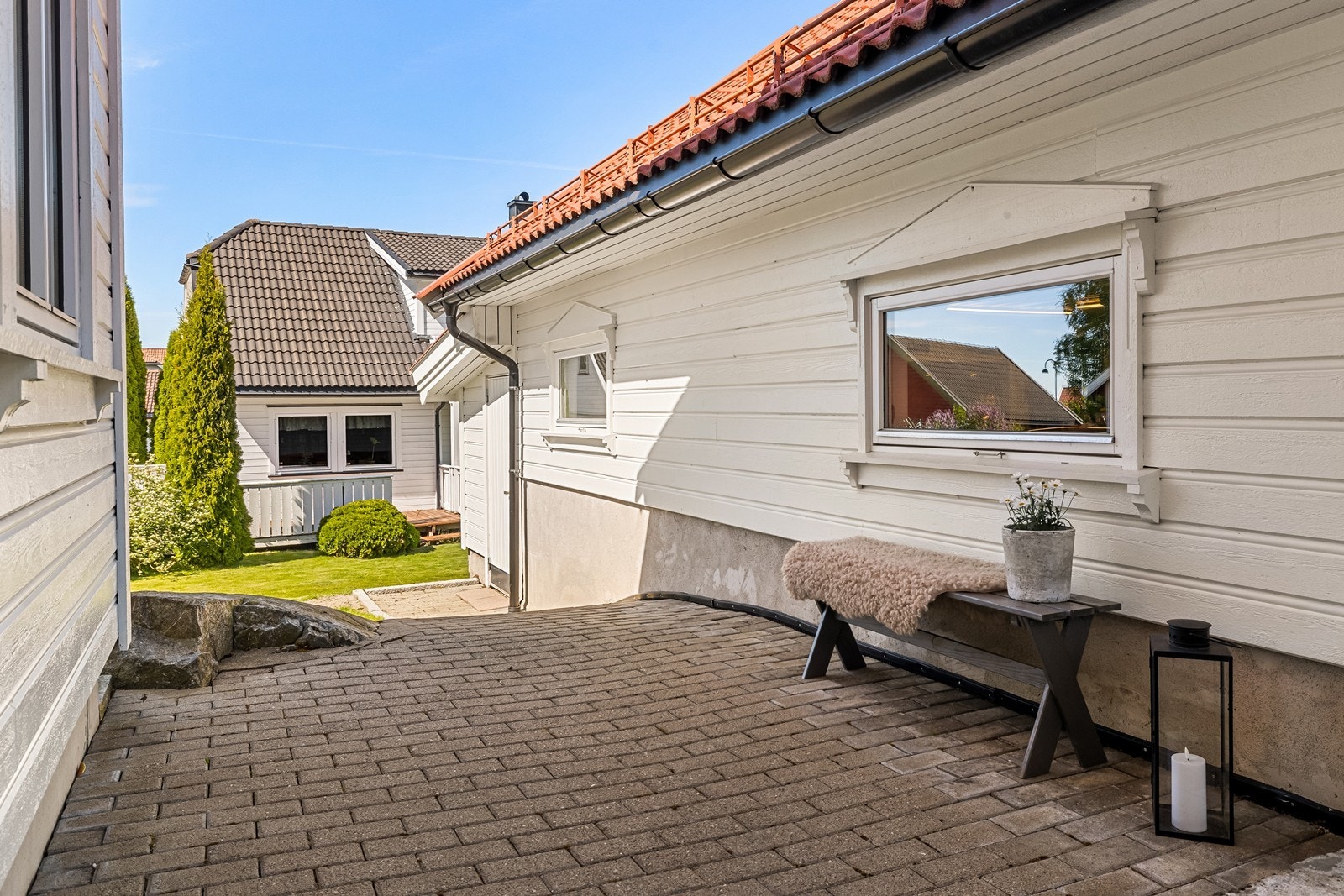 Steinbelagt gårdsplass fører videre til boder i bakkant av garasje. Galleribilde