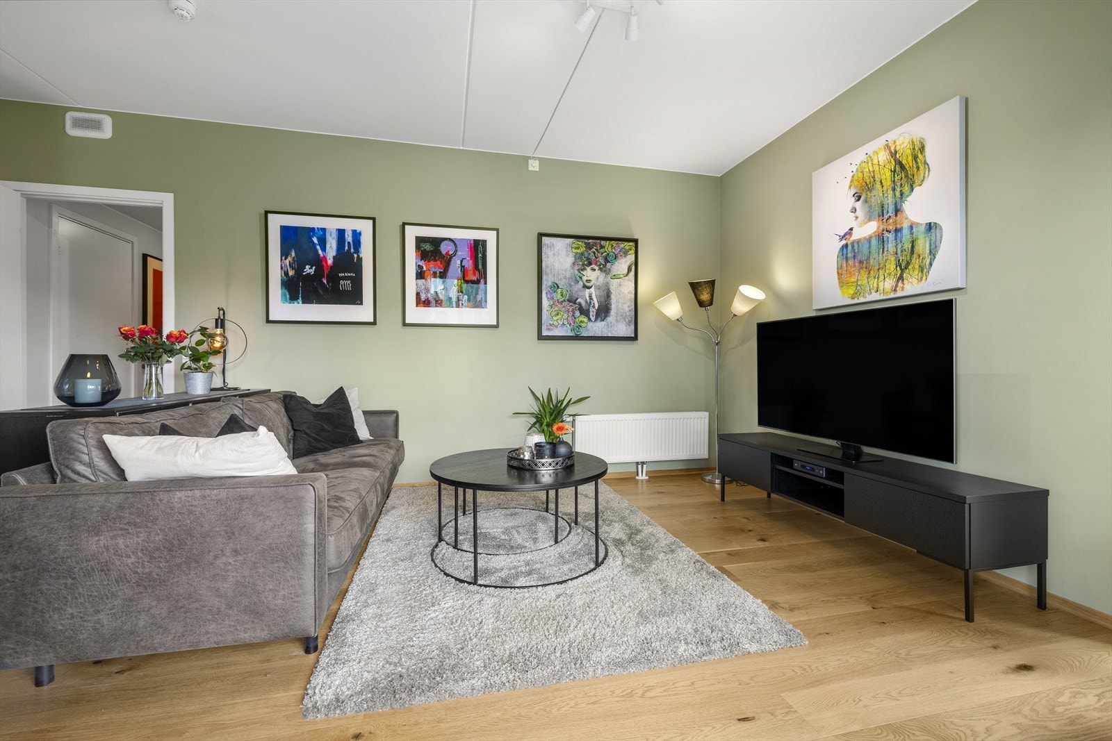 Stuen er malt i en moderne, dempet grønnfarge som skaper en lun og harmonisk atmosfære. Galleribilde