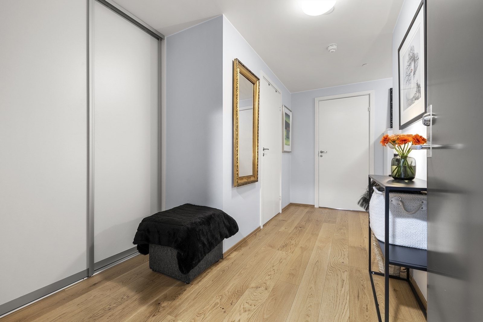 Entreen har parkettgulv, malte vegger og praktisk skyvedørsgarderobe med gode oppbevaringsmuligheter. Galleribilde