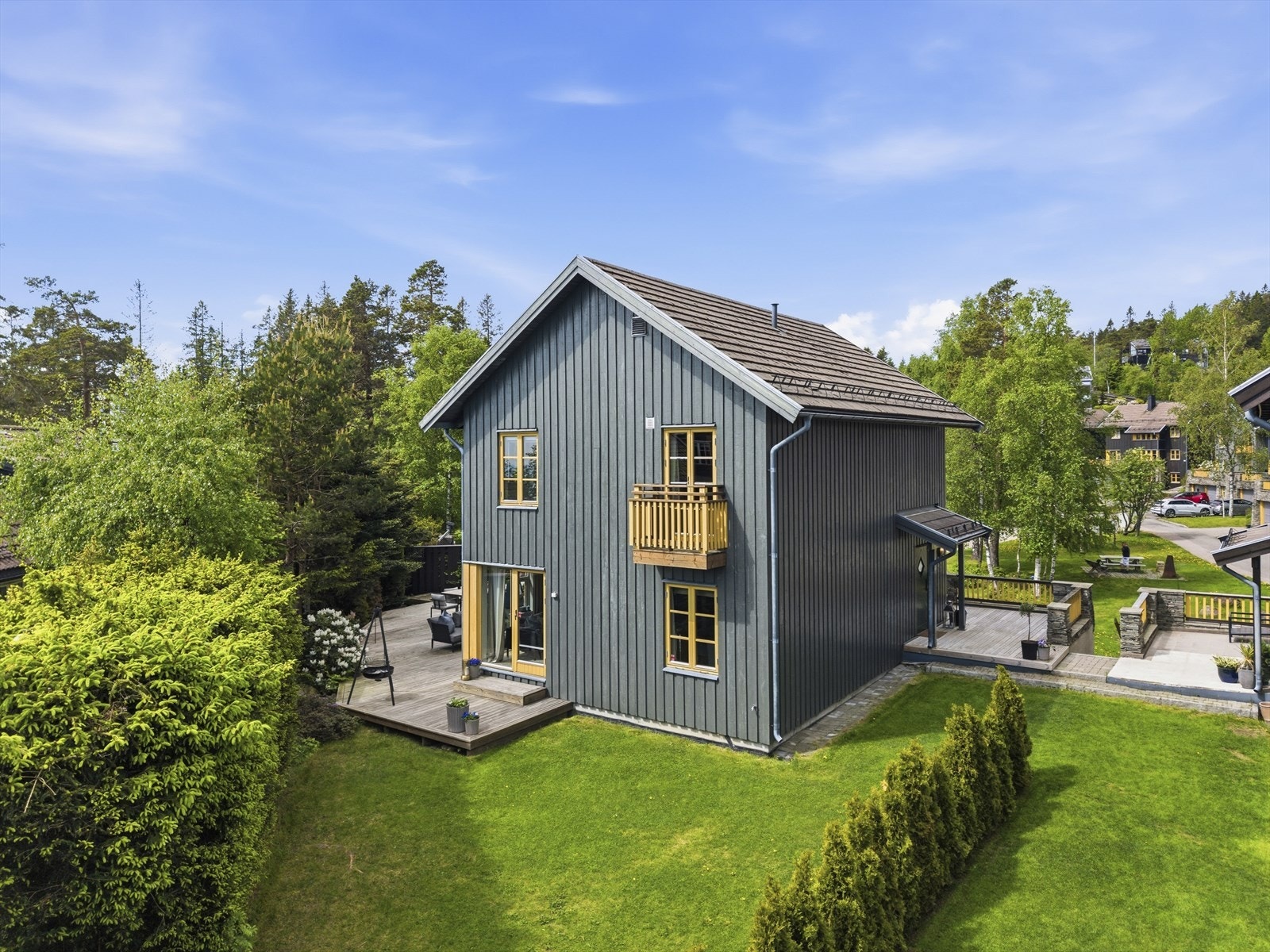 Eiendommen sett fra baksiden, med hage og markterrasse. Hagen er flat, pent opparbeidet og omkranset av hekk. Galleribilde