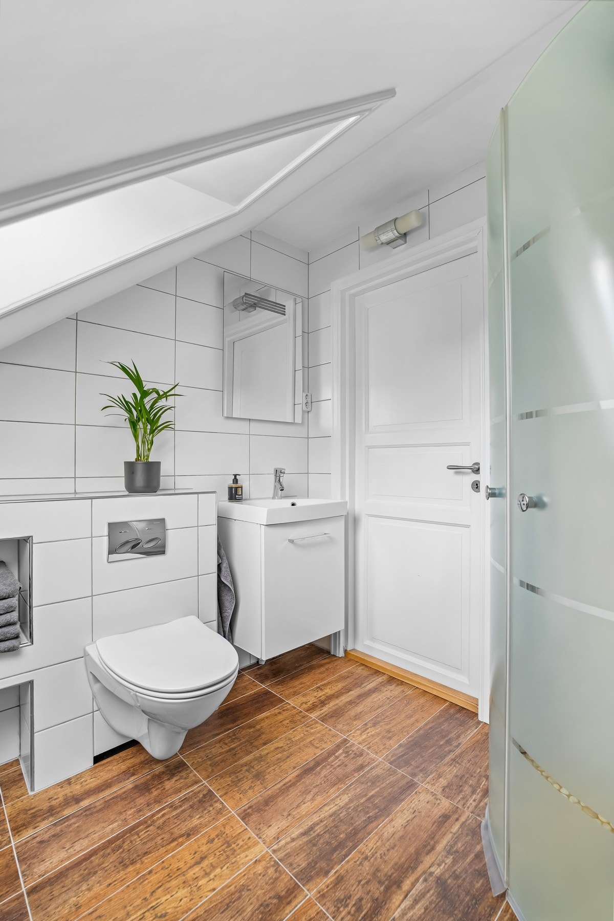 Badet i 2. etasje er innredet med dusjkabinett, vegghengt toalett og servant med underskap. Praktiske nisjer gir ekstra oppbevaringsplass. Galleribilde