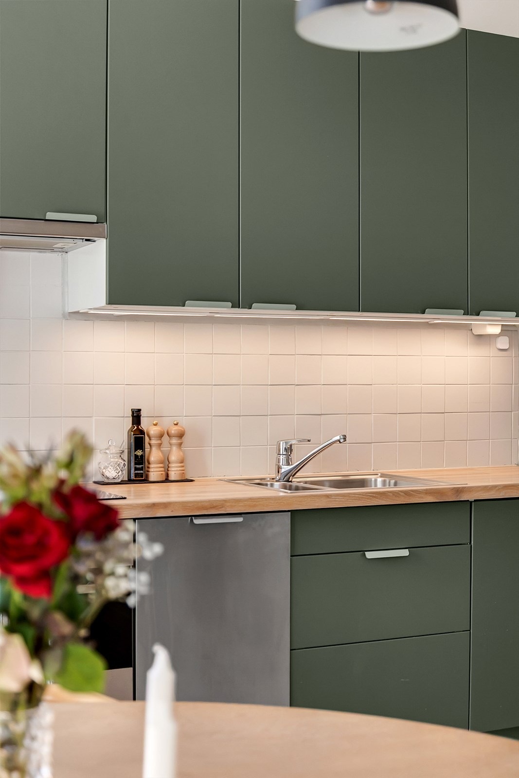 Kjøkkenet ligger i en åpen og sosial løsning mot spisestuen, og fremstår moderne og tidløst med innredning fra IKEA. Innredningen har glatte, grønne fronter og benkeplate i tre med nedfelt oppvaskkum. Galleribilde