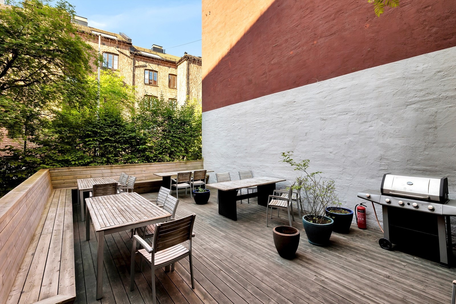 Det er en romslig og solrik uteplass med tredekke og sittegrupper. Galleribilde