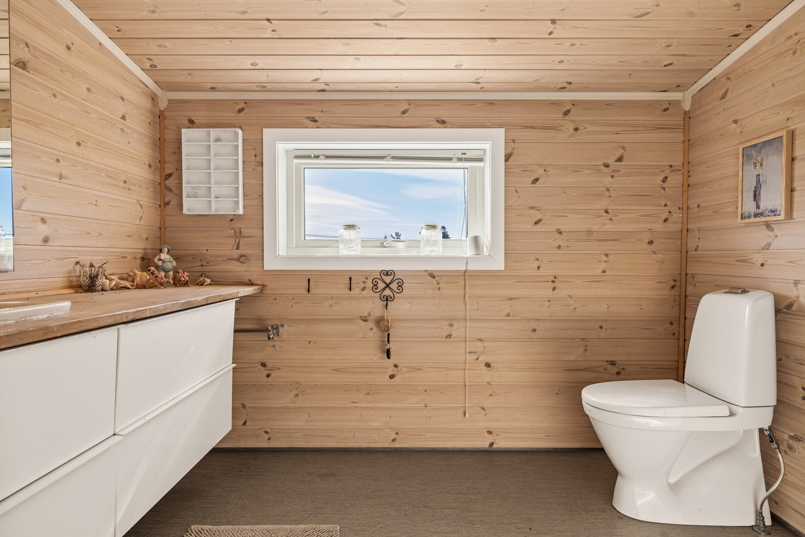 Bad med panel på vegg og tak, servantinnredning og WC. Galleribilde