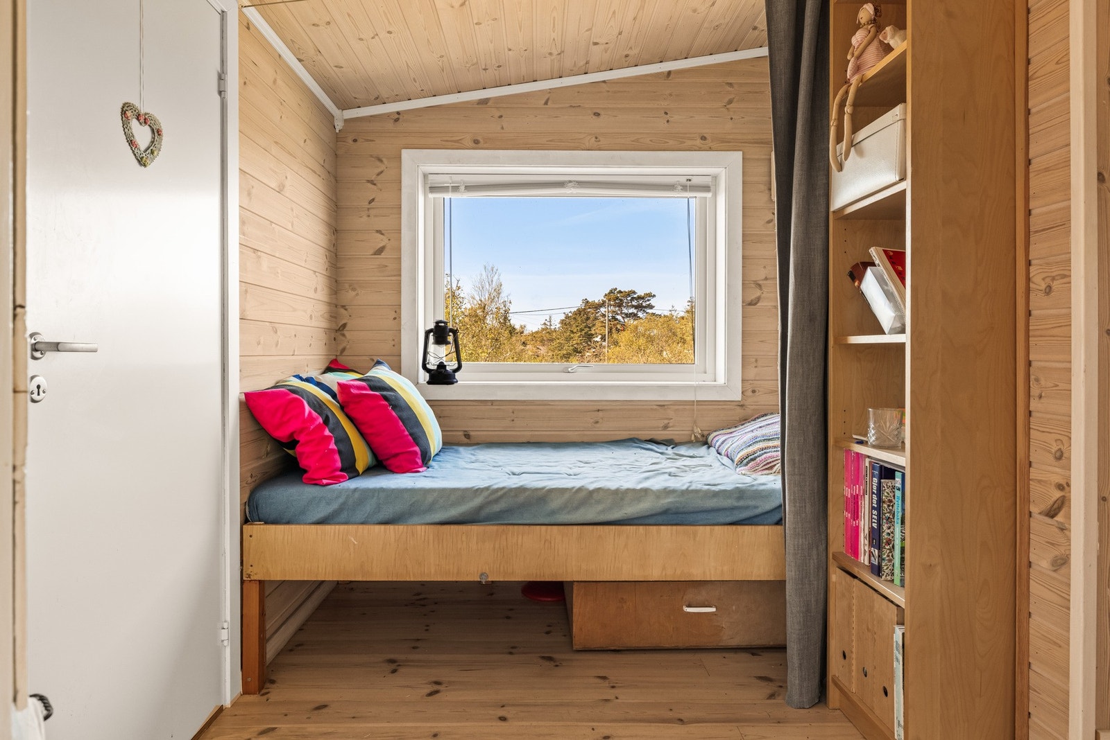 Rom innredet med seng, med utsyn mot svaberg og kystvegetasjon. Rommet er ikke godkjent som soverom, men er i dag innredet og disponert med soveplass. Galleribilde