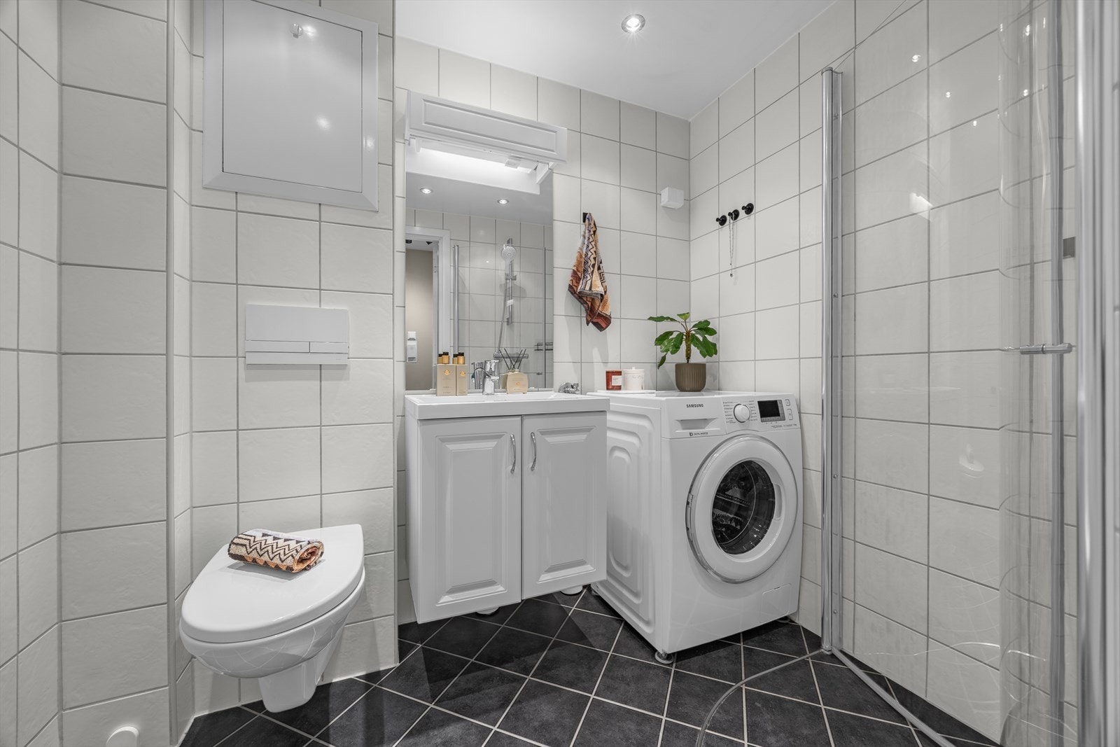Badet har vegghengt toalett, servantinnredning og opplegg for vaskemaskin. Galleribilde