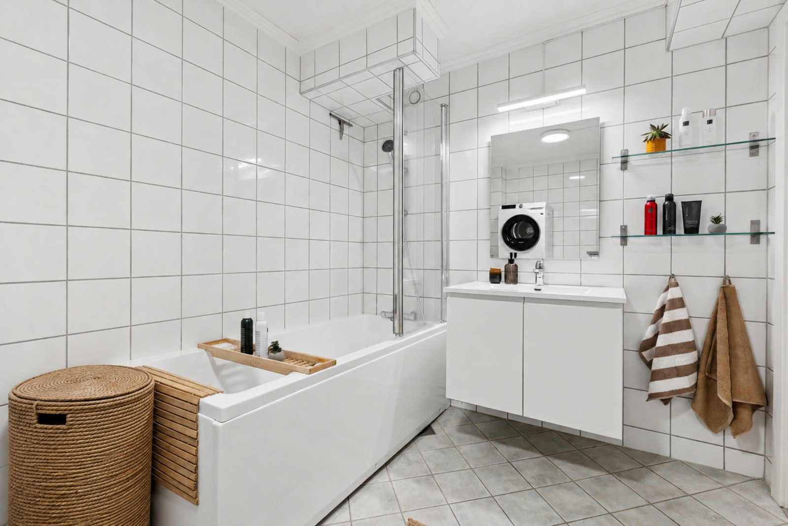 Baderommet har fliser på gulv og vegger, hvitservantinnredning med skapseksjon. Galleribilde