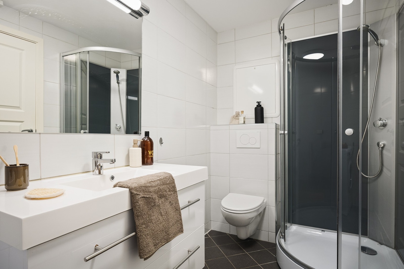 Badet i underetasjen er utstyrt med servant, vegghengt toalett, speil, dusjkabinett og opplegg for vaskemaskin Galleribilde