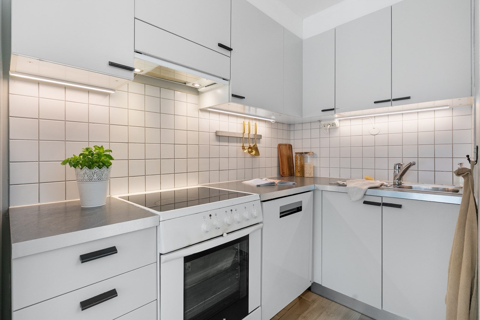 Kjøkkeninnredning med profilerte fronter, laminert benkeplate, oppvaskkum og fliser over benk. Galleribilde