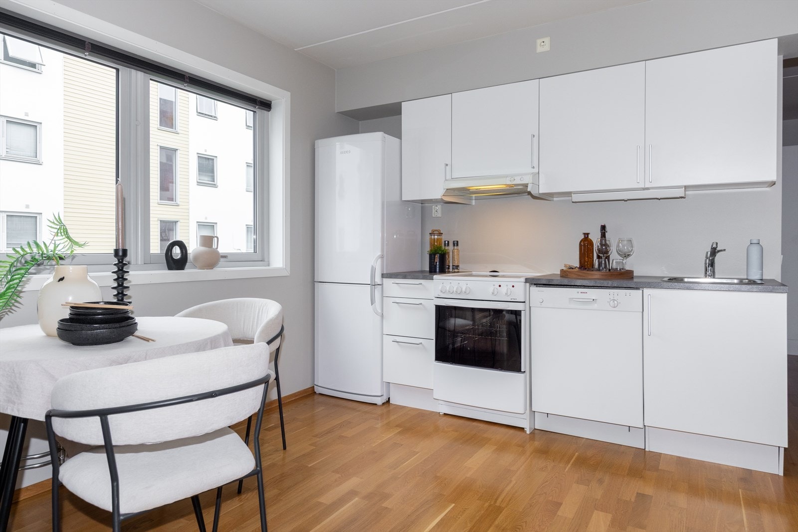 Kjøkken med hvite, glatte fronter og laminat benkeplate med kum. Galleribilde