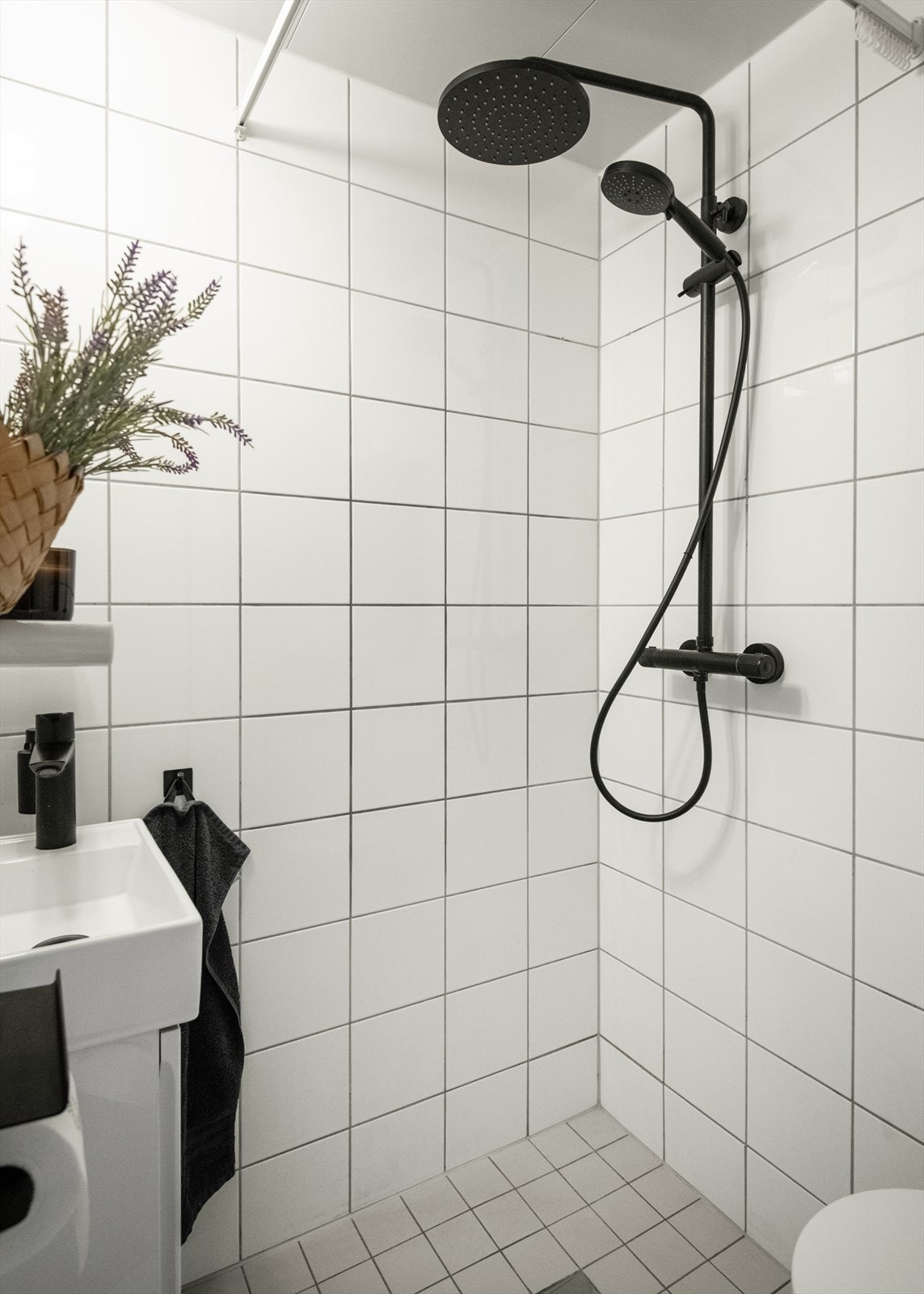 Baderommet er innredet med regndusj, vegghengt servant og toalett med svarte detaljer som gir et gjennomført og moderne uttrykk. Galleribilde