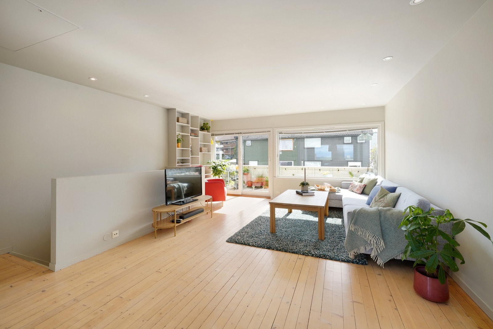 Stuen føles lys med mye naturlig lysinnslipp fra store vinduer og skyvedør. Loft til lagring. Galleribilde