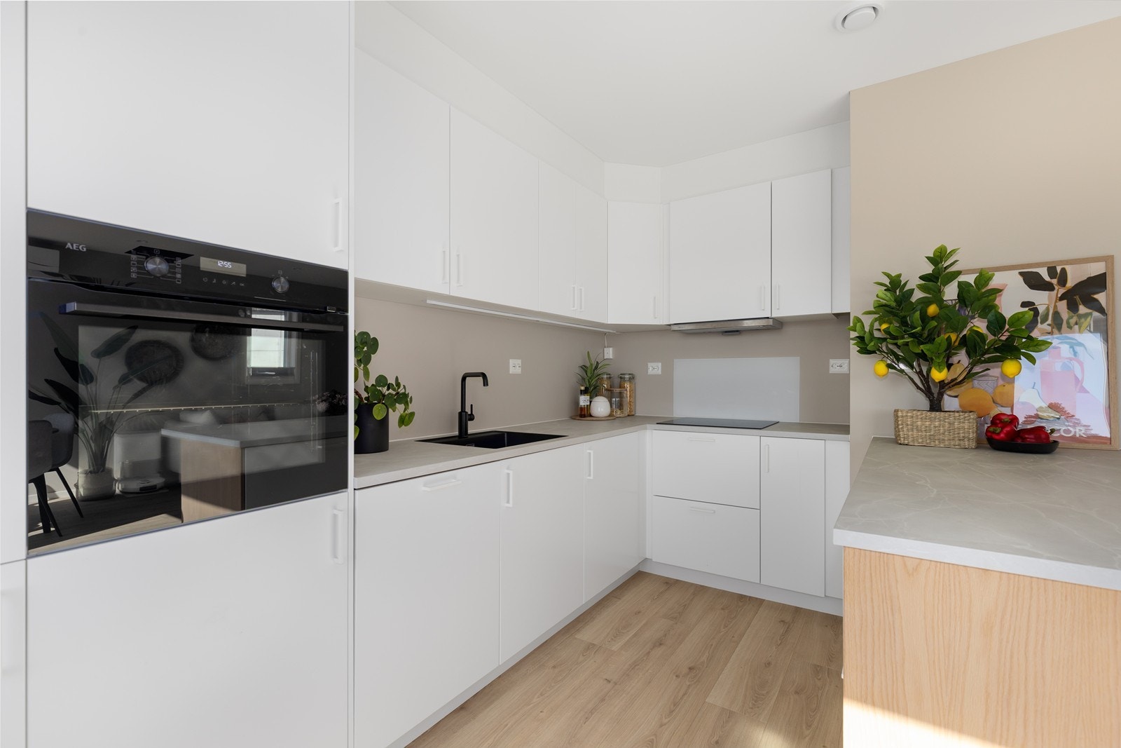 Kjøkkenet har stilrene, glatte hvite fronter kombinert med laminert benkeplate, som gir et moderne og tidløst uttrykk. Det er integrerte hvitevarer bestående av oppvaskmaskin, kjøleskap, induksjonstopp og stekeovn. Galleribilde