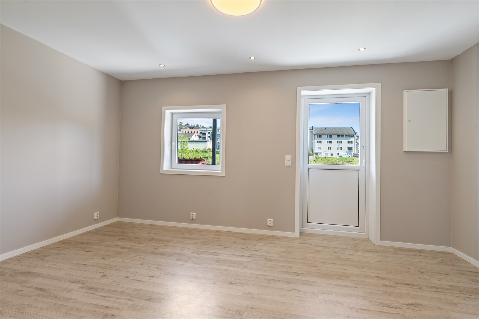 Lyst oppholdsrom med downlights i taket og utgang til uteplass. Galleribilde