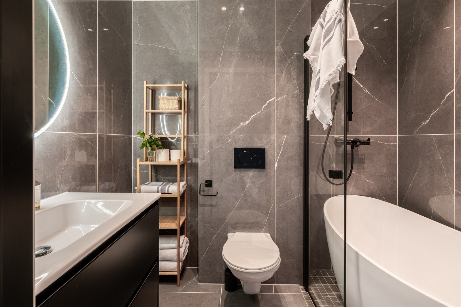 Badet som er tilknyttet kjellerstuen. Badet er innredet med veggmontert toalett, heldekkende servant nedfelt i underskap med speil med integrert lys og badekar. Galleribilde