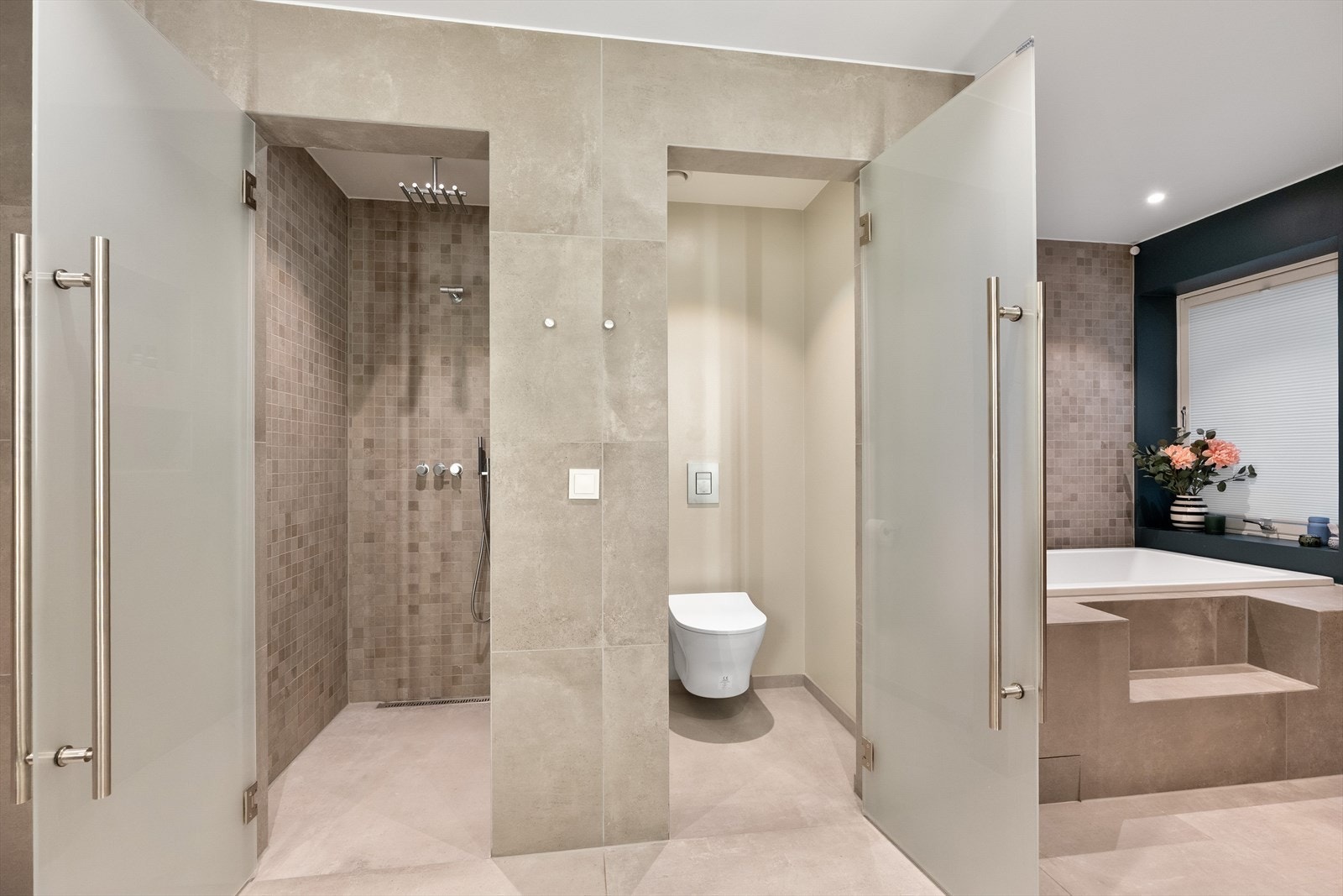 Badet er inndelt i soner, med separate nisjer for dusj og toalett, samt et innfliset badekar. Galleribilde