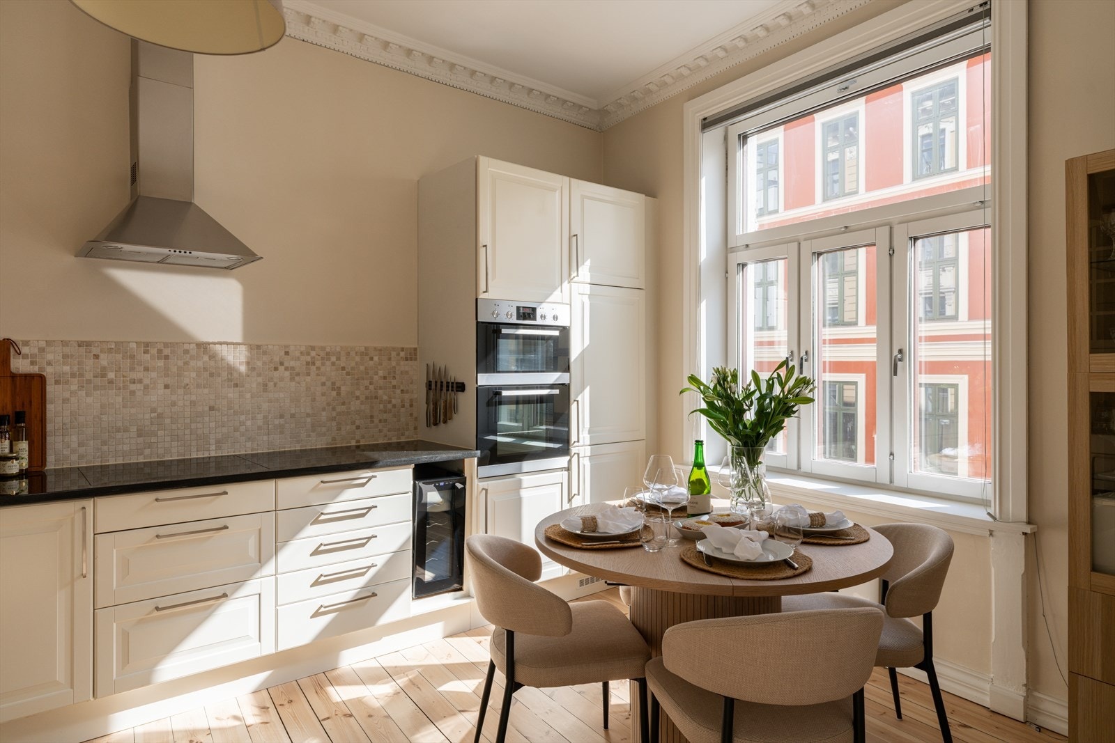Kjøkkeninnredningen har profilerte fronter i klassisk stil, harmonisk tilpasset leilighetens arkitektur og uttrykk. Benkeplate i steinmateriale gir gode arbeidsflater, og mosaikkfliser over benken tilfører et eksklusivt preg. Galleribilde