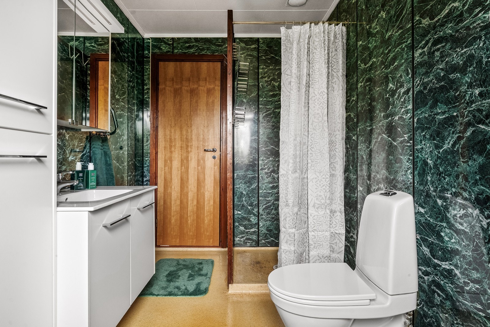 Badet i første etasje har terrasso på gulv, baderomsplater på veggene og en dusjnisje med oppkant. Galleribilde