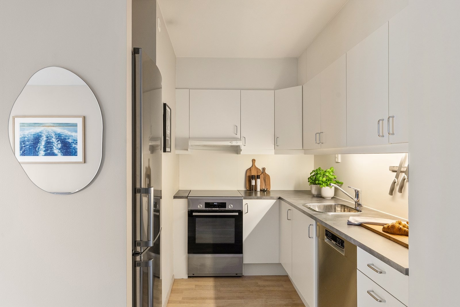 Innredningen har glatte fronter, laminat benkeplate og nedfelt vaskekum. Belysning over benkeplaten gir gode arbeidsforhold, og kjøkkenet er utstyrt med opplegg for komfyr og oppvaskmaskin samt ventilator over kokeplassen. Galleribilde