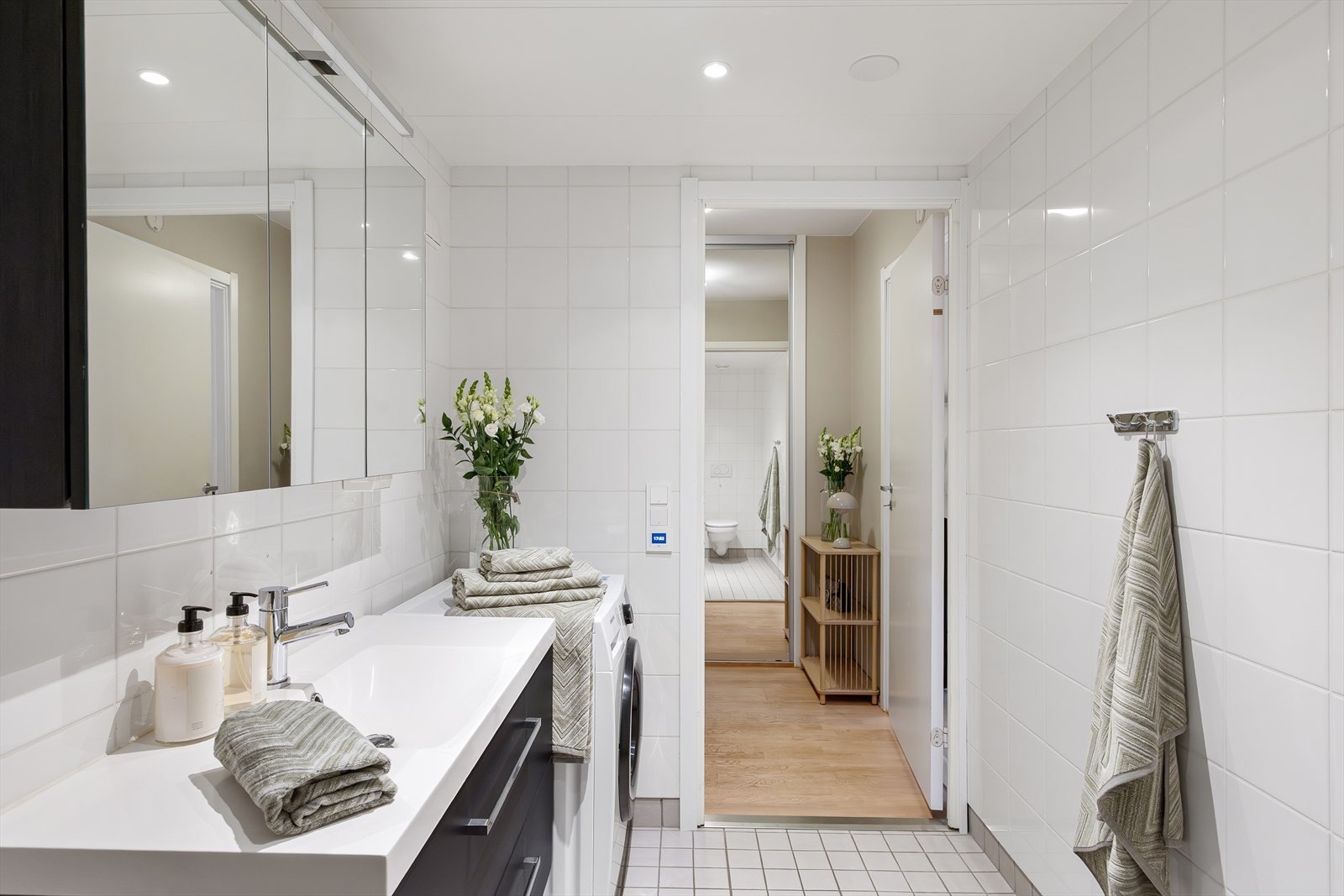Badet er innredet med vegghengt toalett, servant med underskap, speil med belysning og dusjhjørne med svingbar glassdør. Galleribilde