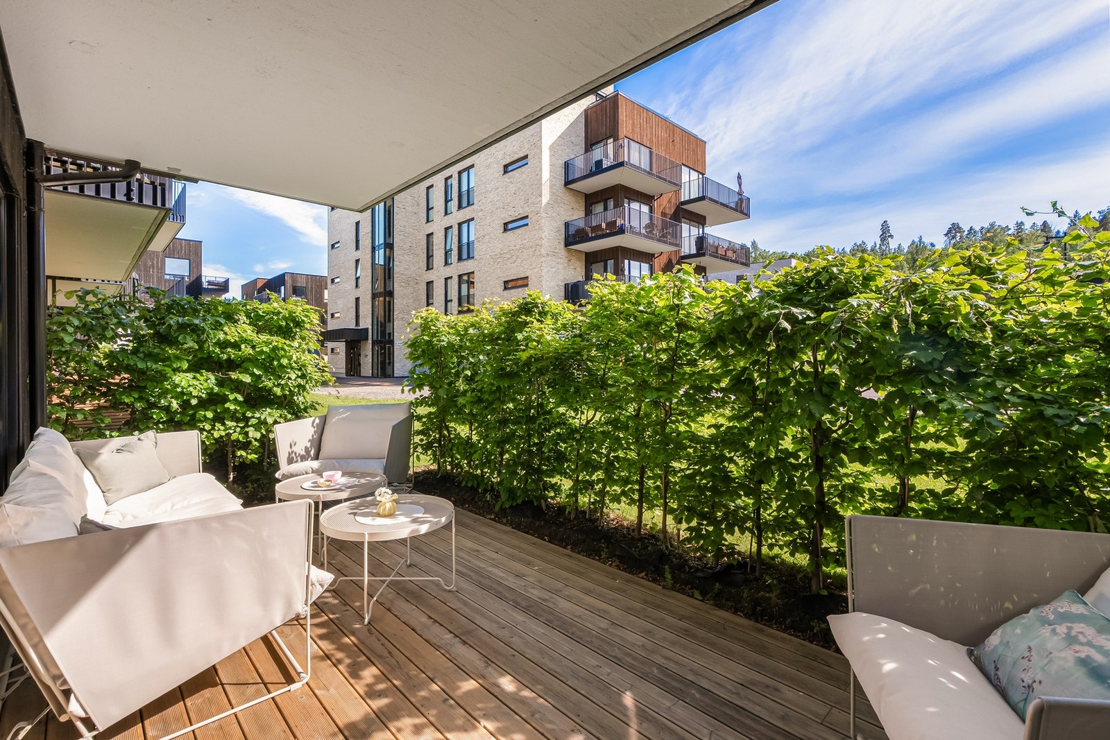 Terrassen er overbygget, har terrassebord på gulv og god plass til sittegrupper etter eget ønske og behov. Den grønne hekken gjør at du sitter lunt og skjermet for innsyn. Galleribilde