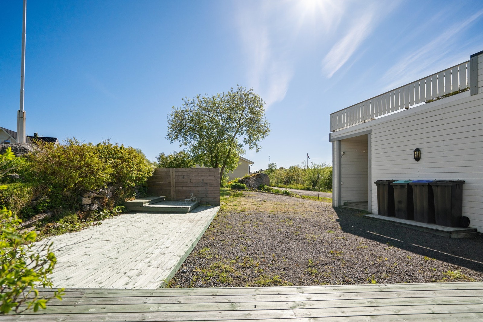 Tomten er opparbeidet med gruset gårdsplass og terrasseplatting. Galleribilde