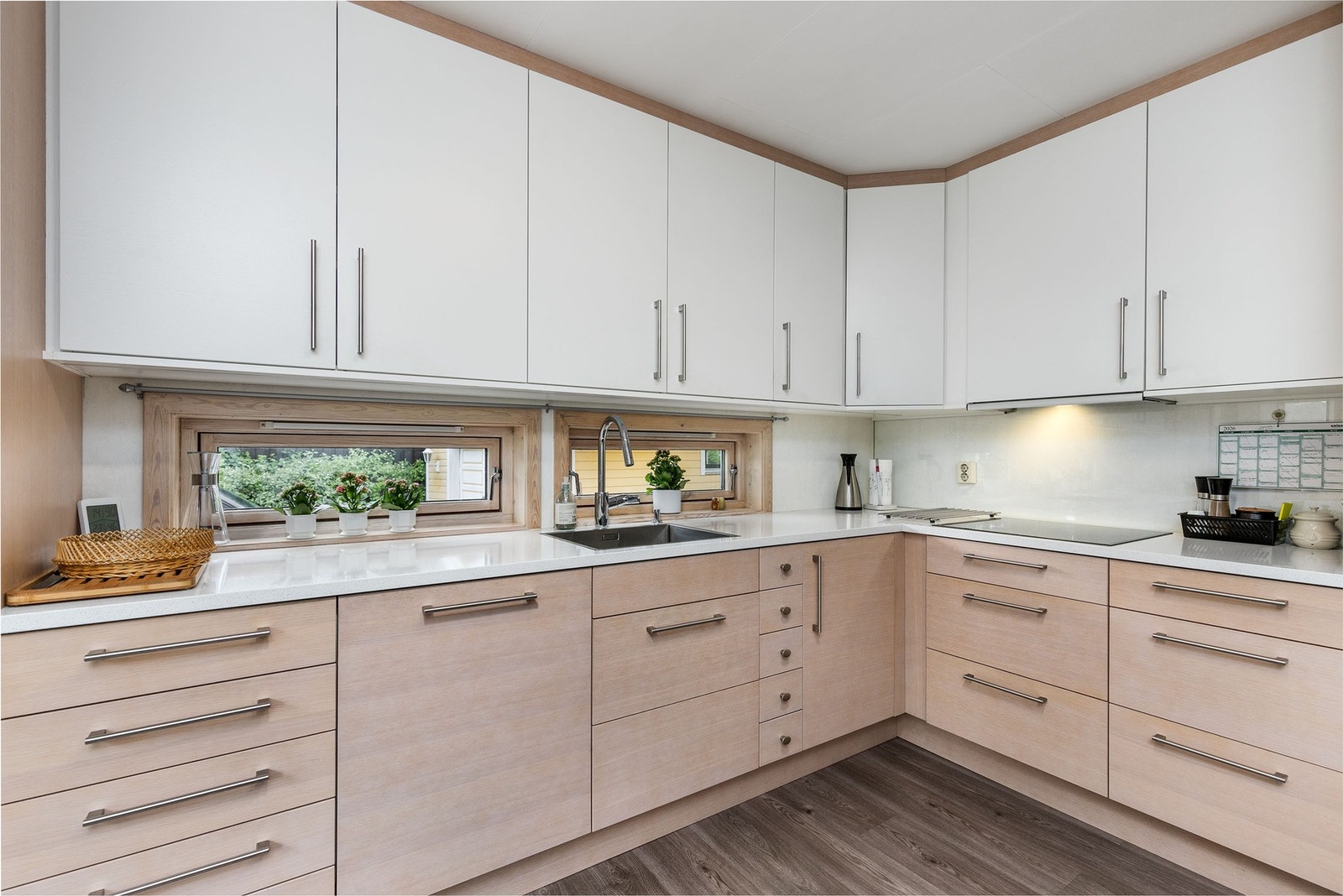 Kjøkkeninnredning med glatte fronter i tidsriktig farge. Påkostet benkeplate av silestone, med nedfelt kum Galleribilde
