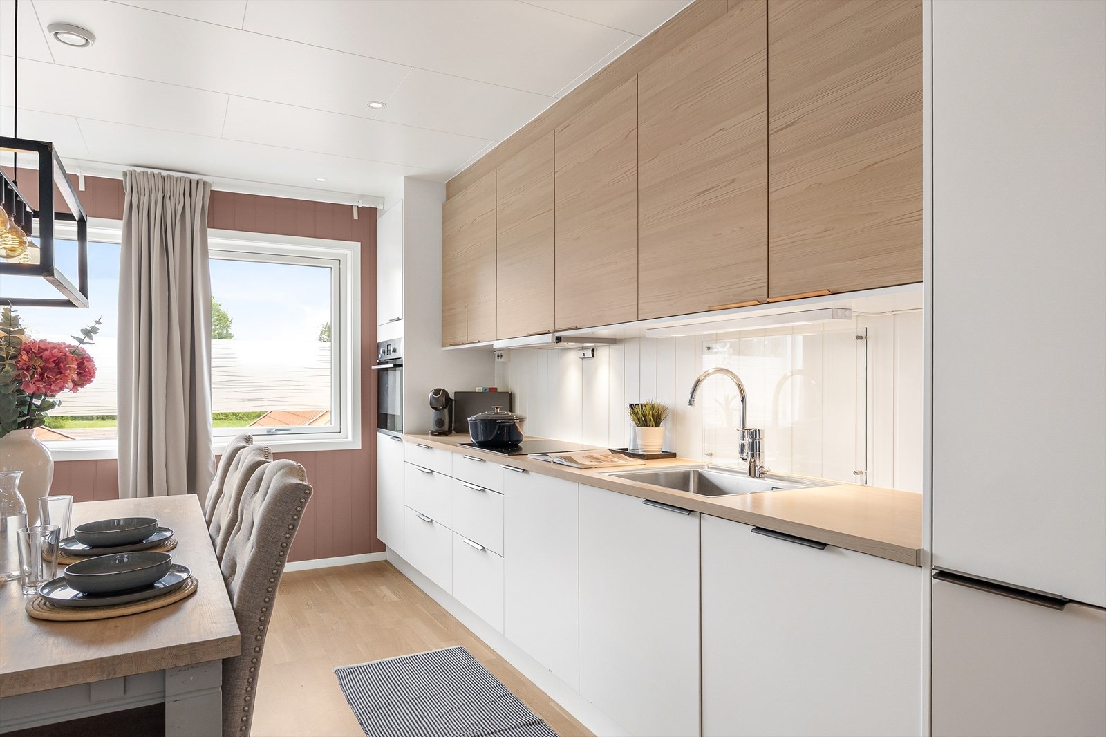 Kjøkkeninnredningen har trefargede og hvite glatte fronter, samt laminert benkeplate. Galleribilde