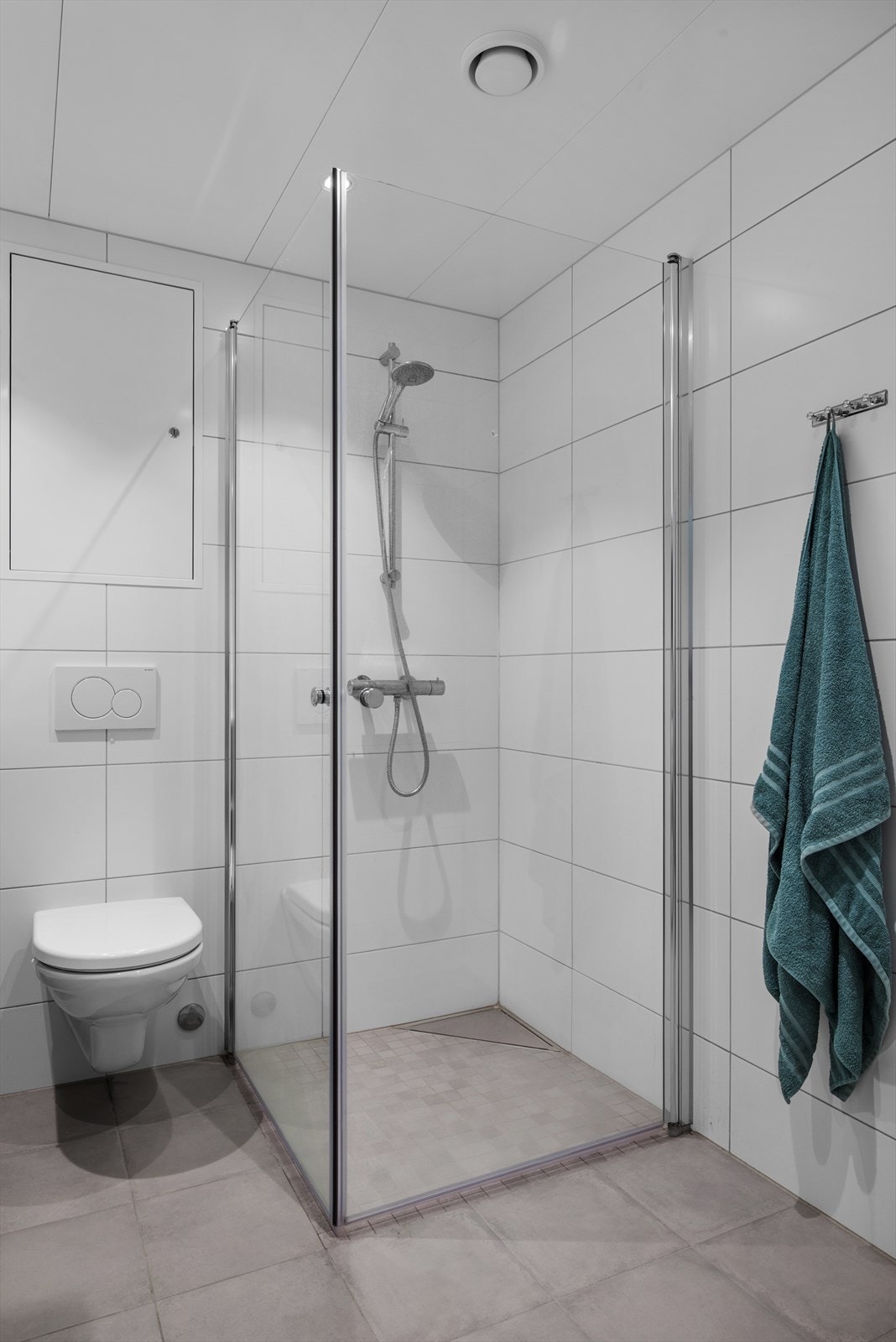 Badet er utstyrt med innfellbare dusjdører, vegghengt toalett, servantskap, mekanisk ventilasjon og opplegg for vaskemaskin. Galleribilde