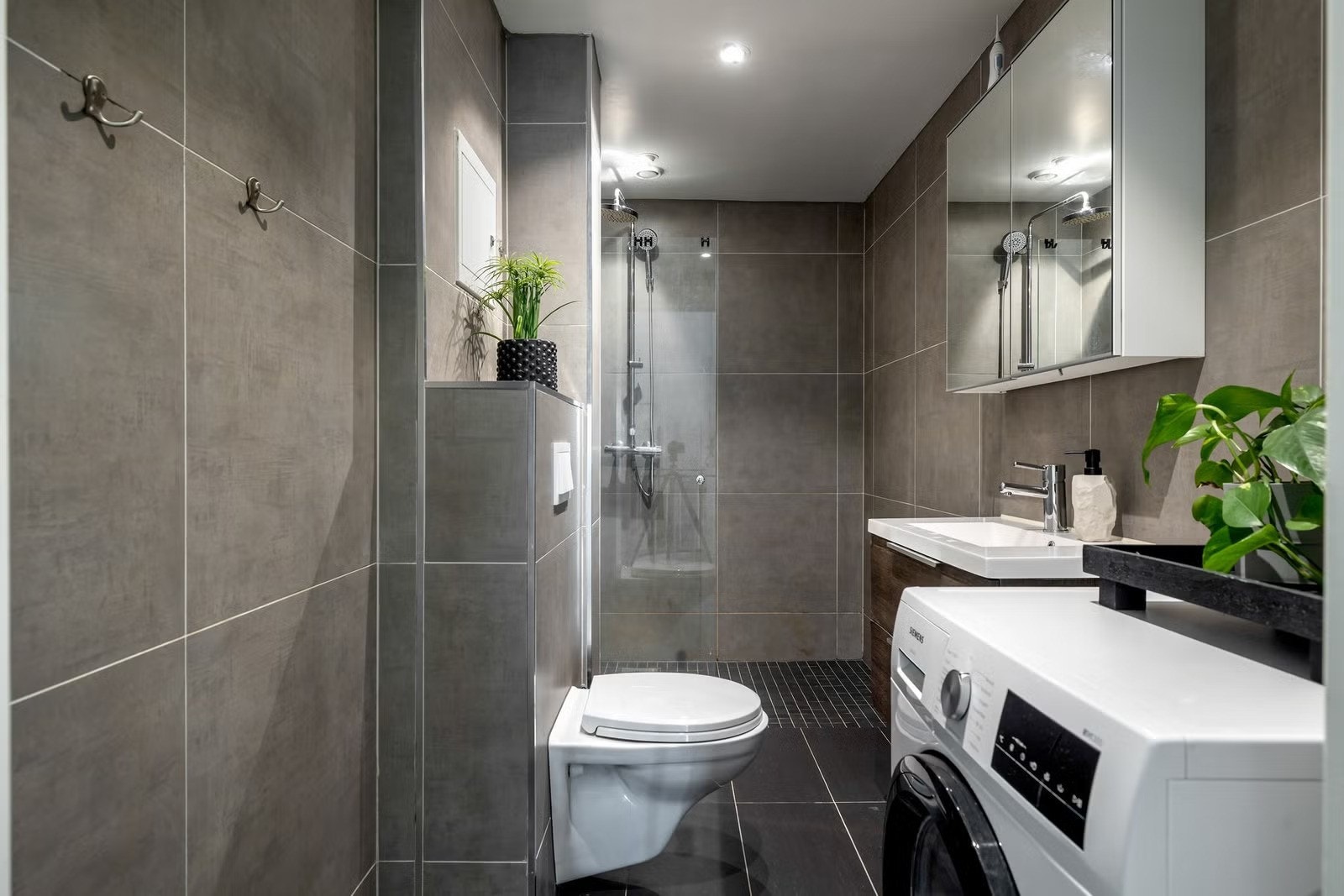 Badet i 1. etasje er fra 2016 og har flislagte vegger og gulv. Her er det vaskemaskin som følger med Galleribilde