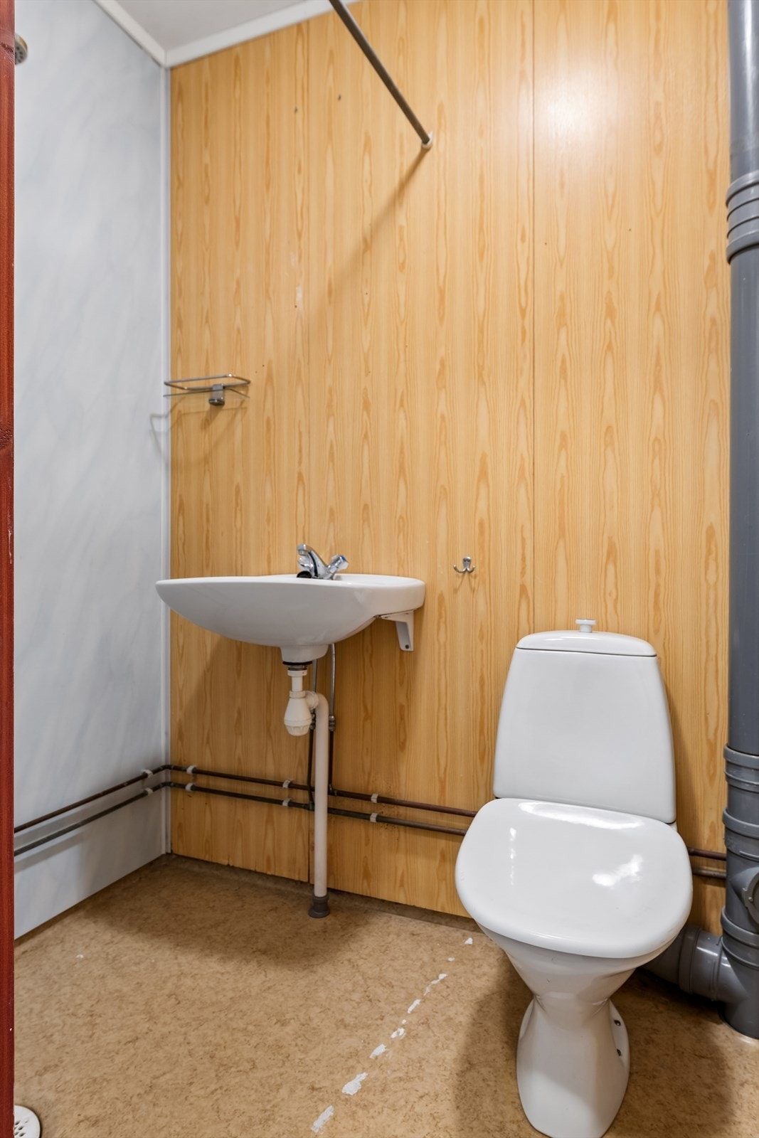 Badet er fra byggeåret og har våtromsplater på veggene og belegg på gulvet. Rommet er utstyrt med gulvmontert toalett og vegghengt servant. Galleribilde