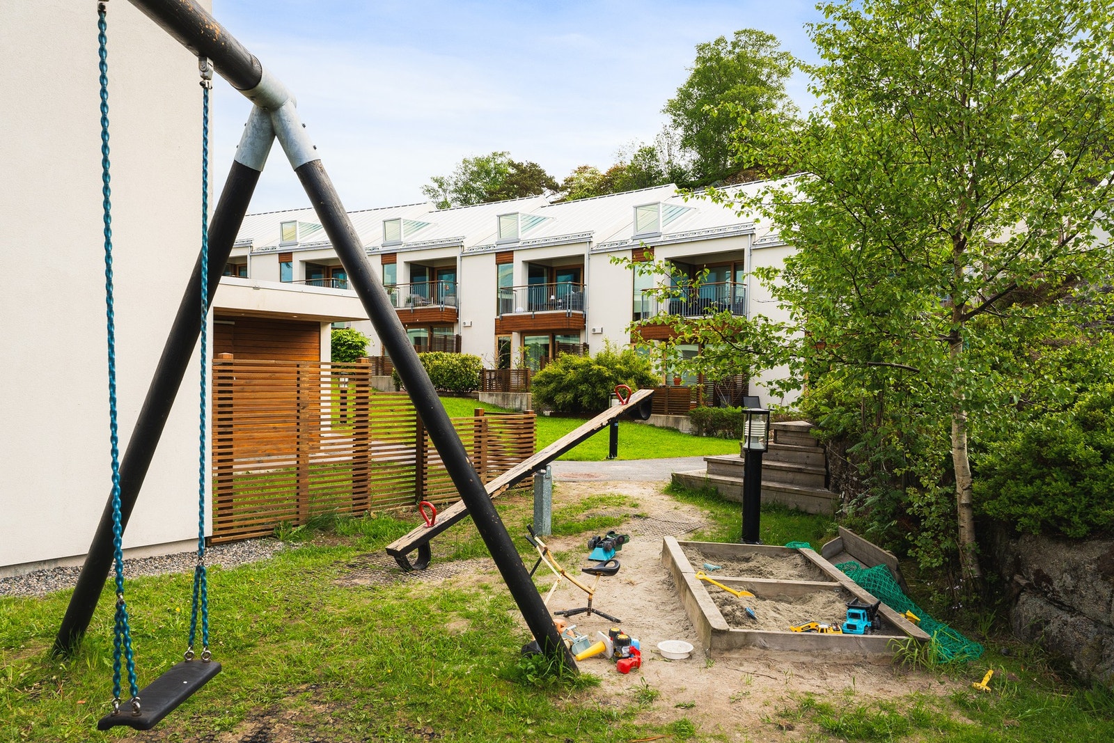 Det er et veldig koselig fellesområde med en stor plen tilknyttet en lekeplass. Her kan ungene leke og sykle under enkelt oppsyn fra huset. Galleribilde