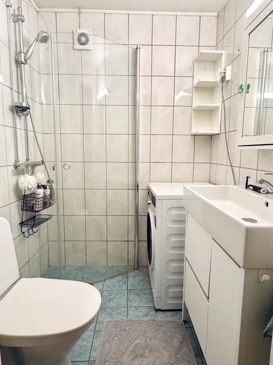 Flislagt bad med toalett, servant, hjørnedusj og vaskemaskin. Galleribilde