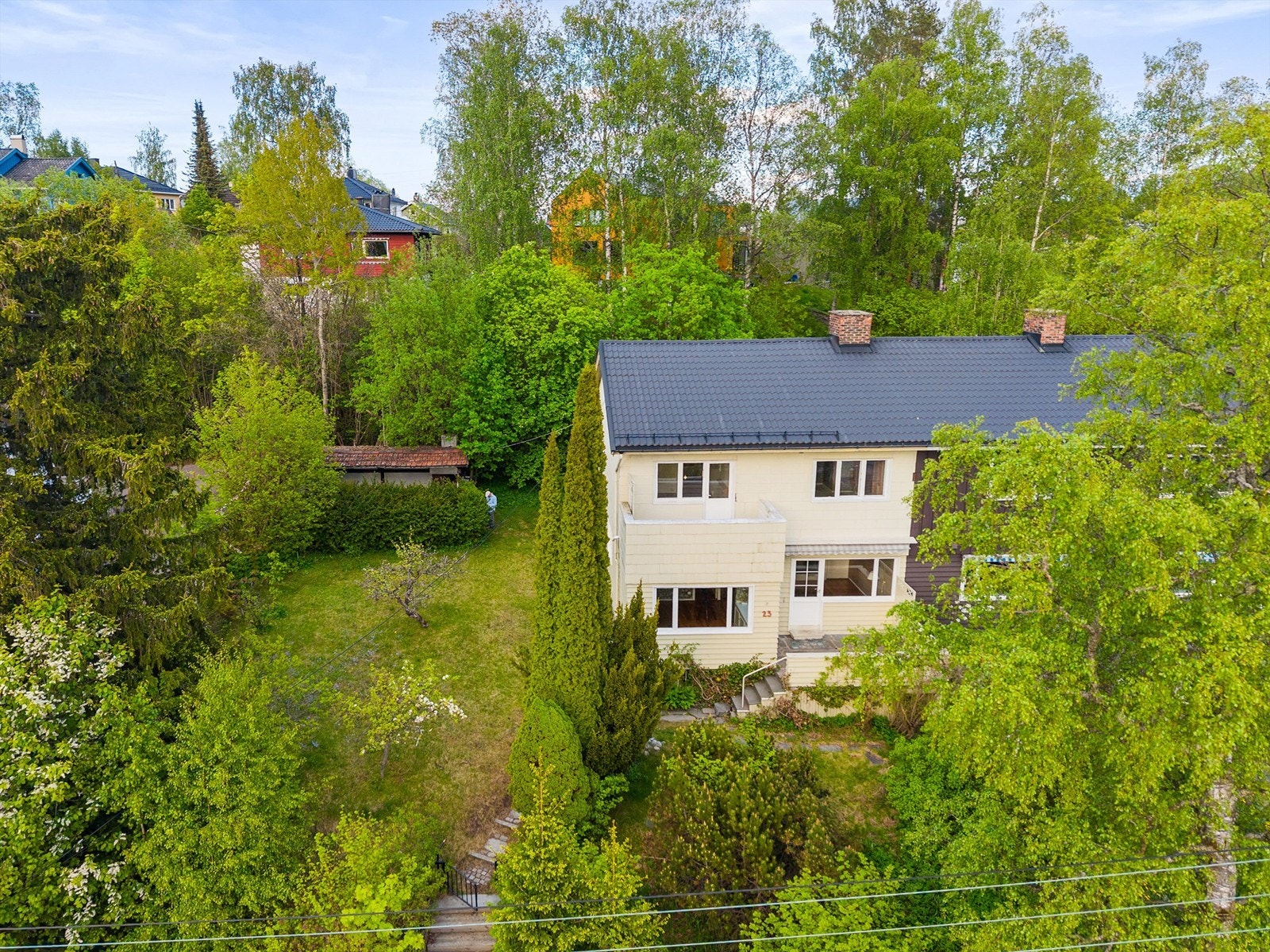 Hyggelig hage med plen og beplantning som omkranser boligen. Galleribilde